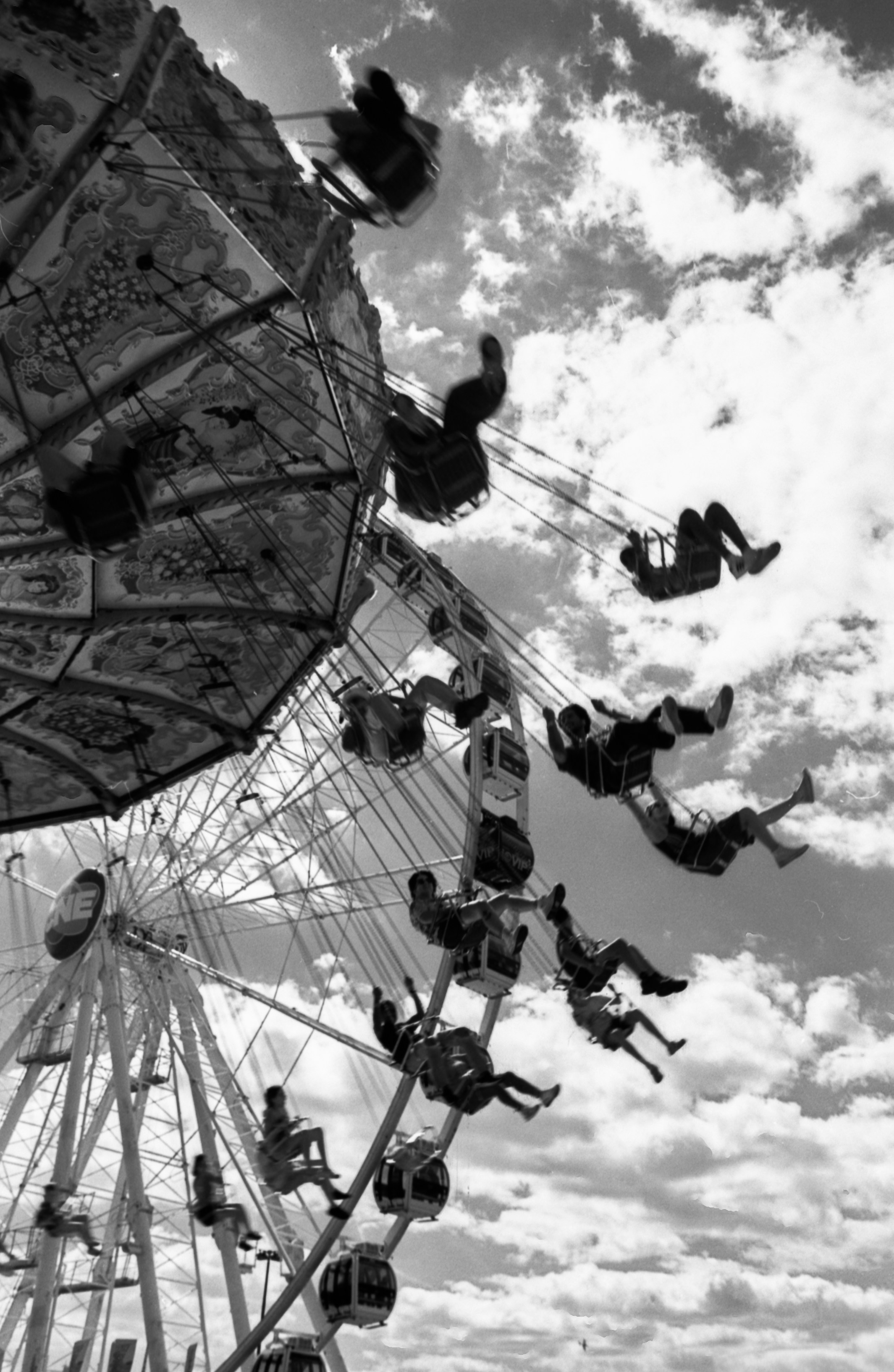 People in swinging chairs on a carousel ride against a cloudy sky