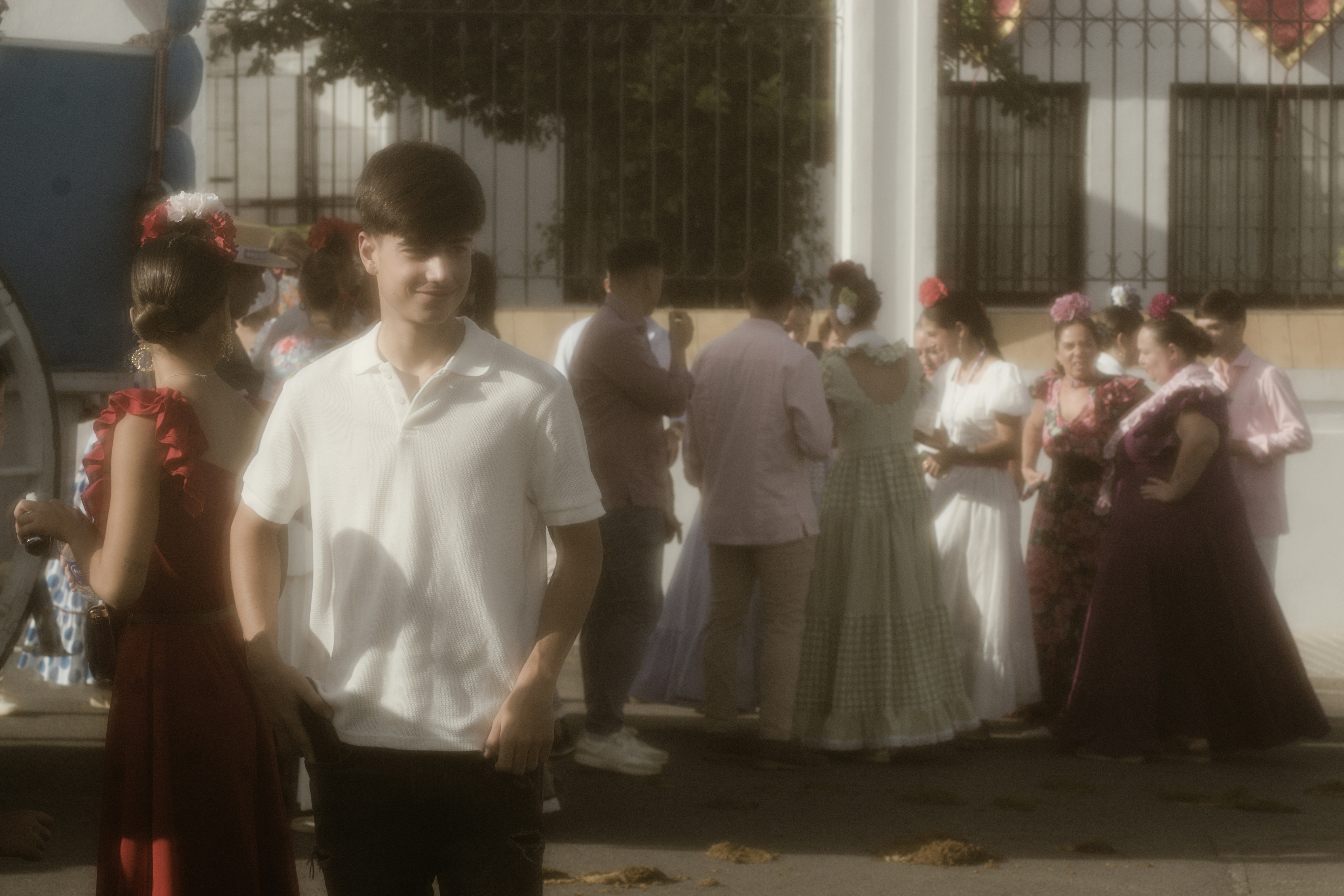 A young man in a white polo shirt among people in traditional Spanish attire