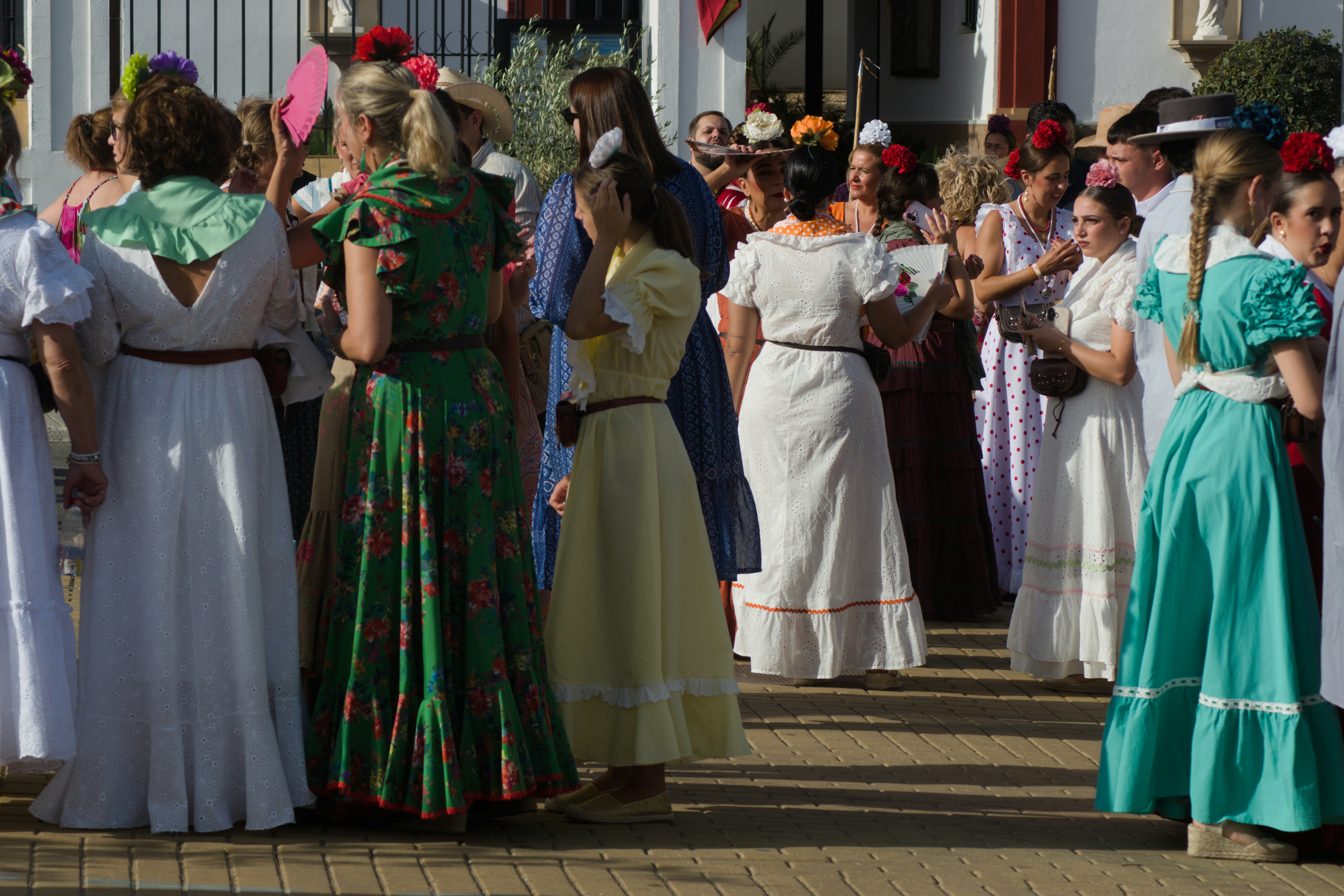 A group of women in colorful traditional dresses standing on a paved plaza