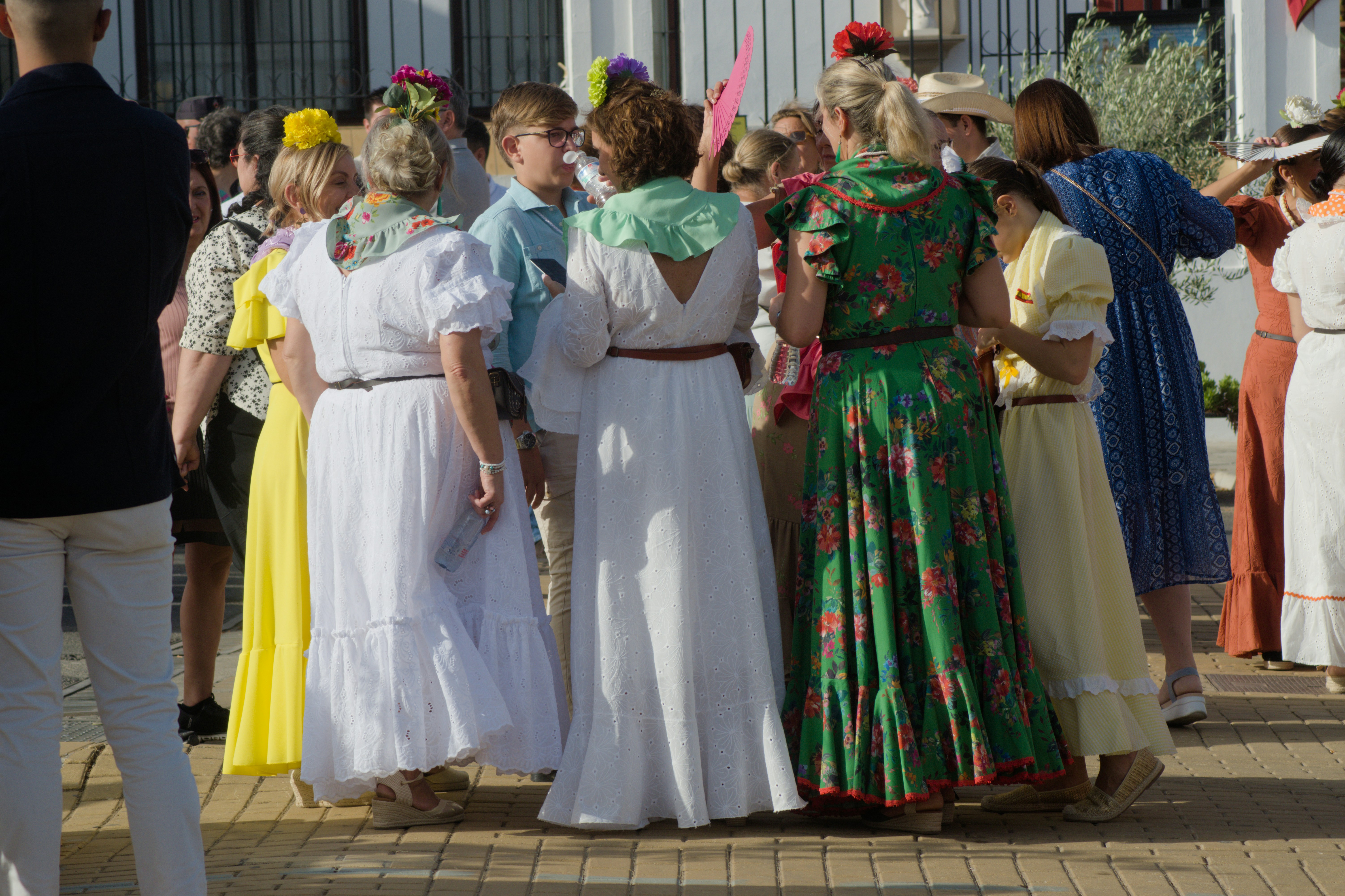 A group of people in colorful traditional dresses standing together on a sunny street