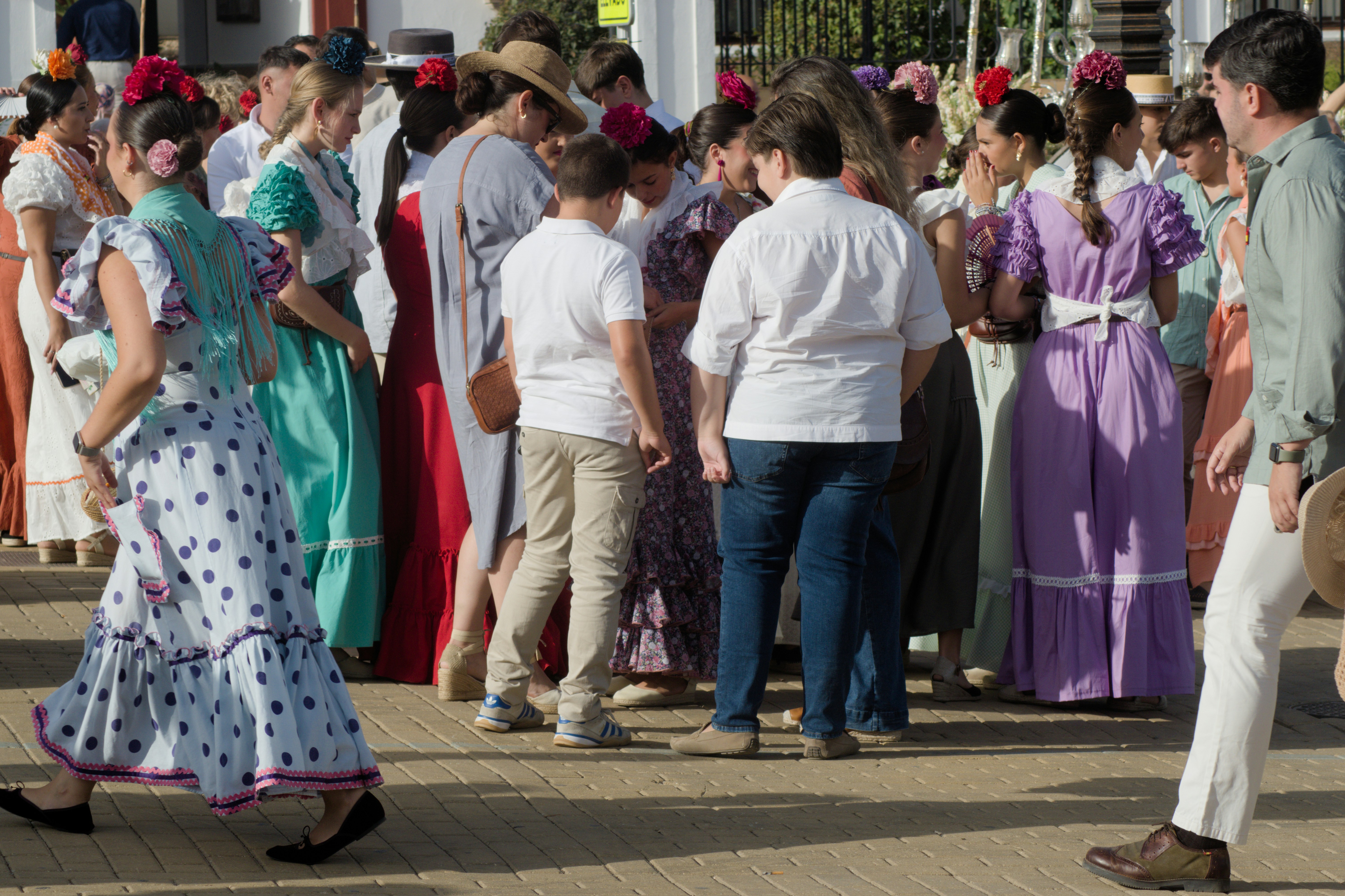 A group of people in traditional Spanish attire standing on a paved plaza