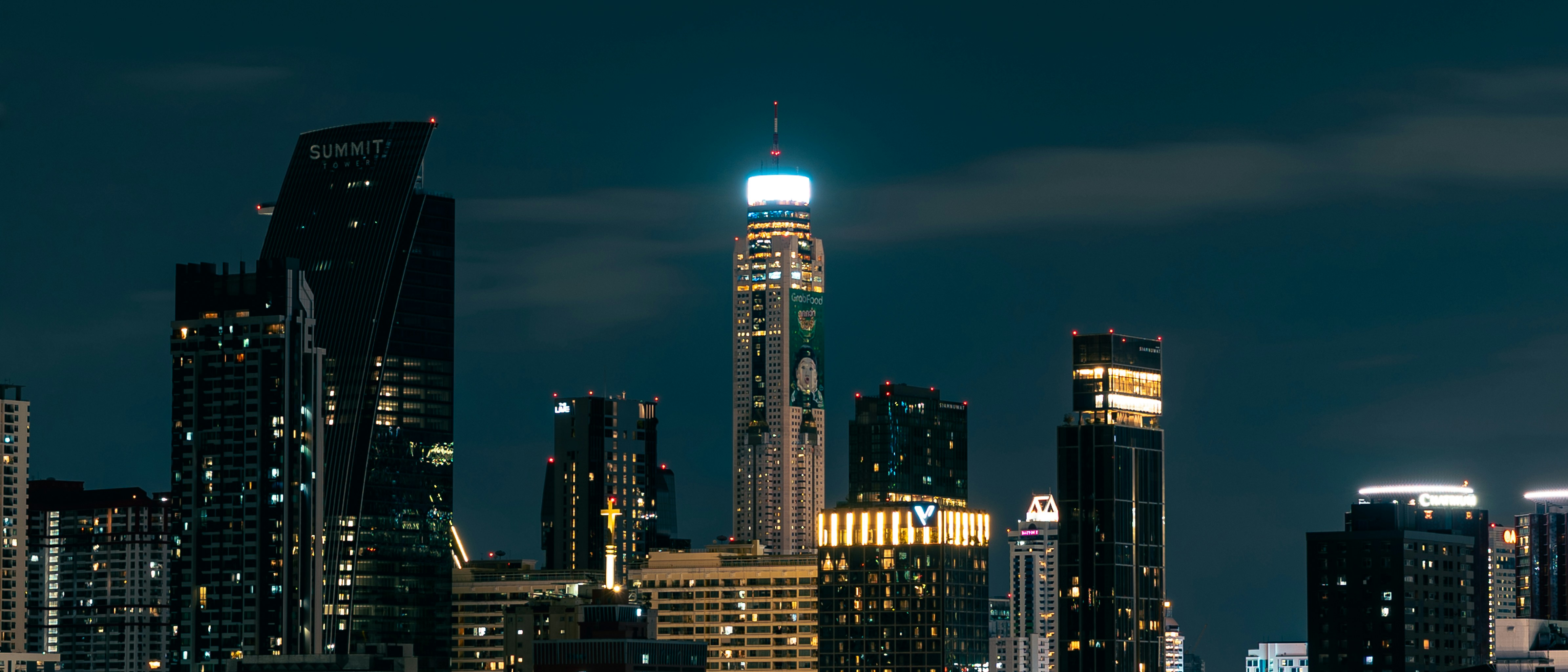 Illuminated skyscrapers in a city skyline at night under a dark sky