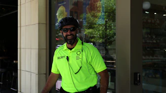 A security guard in a neon yellow shirt and helmet standing in a doorway