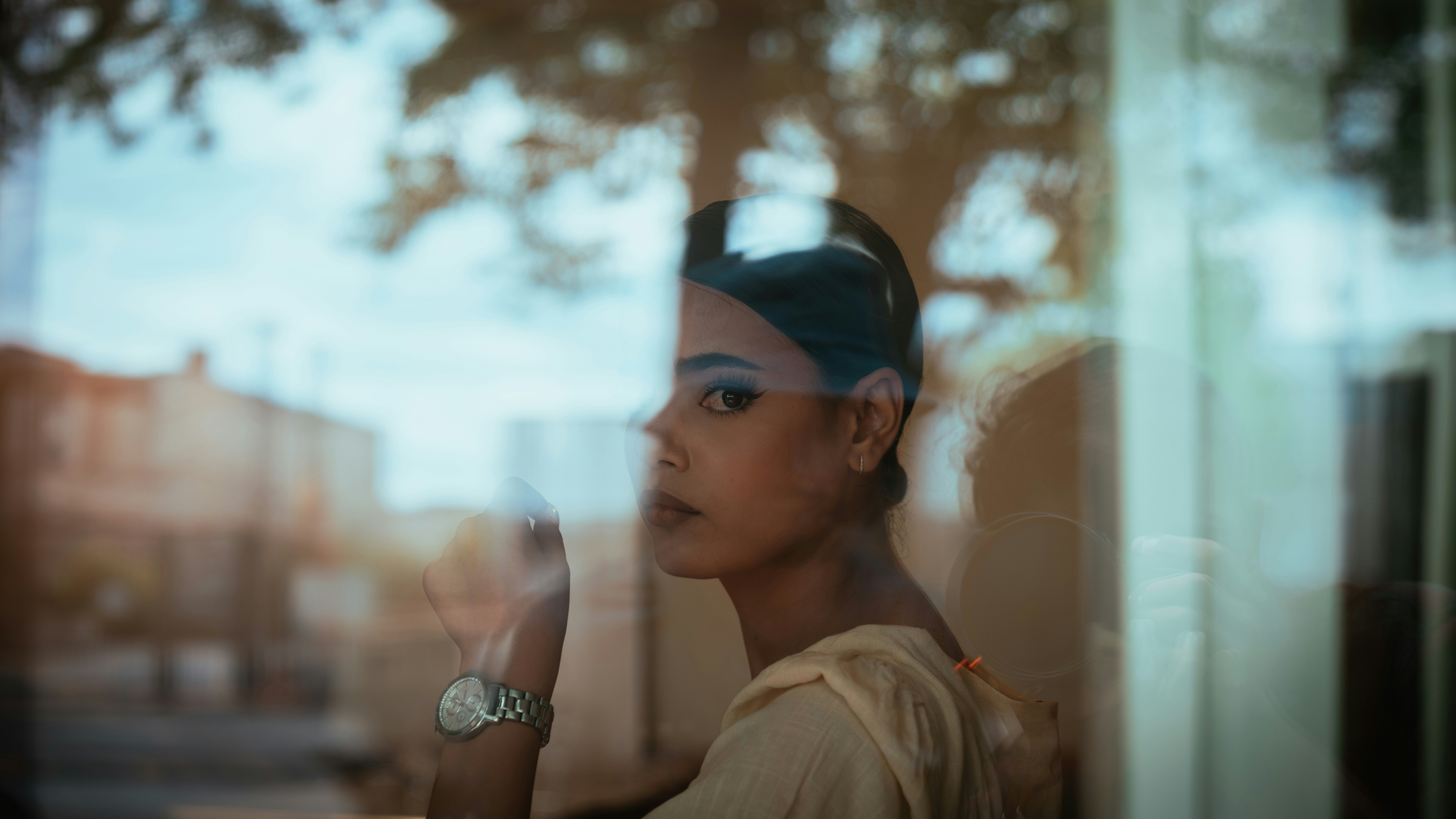 A woman with dark hair in a bun looking through a glass window