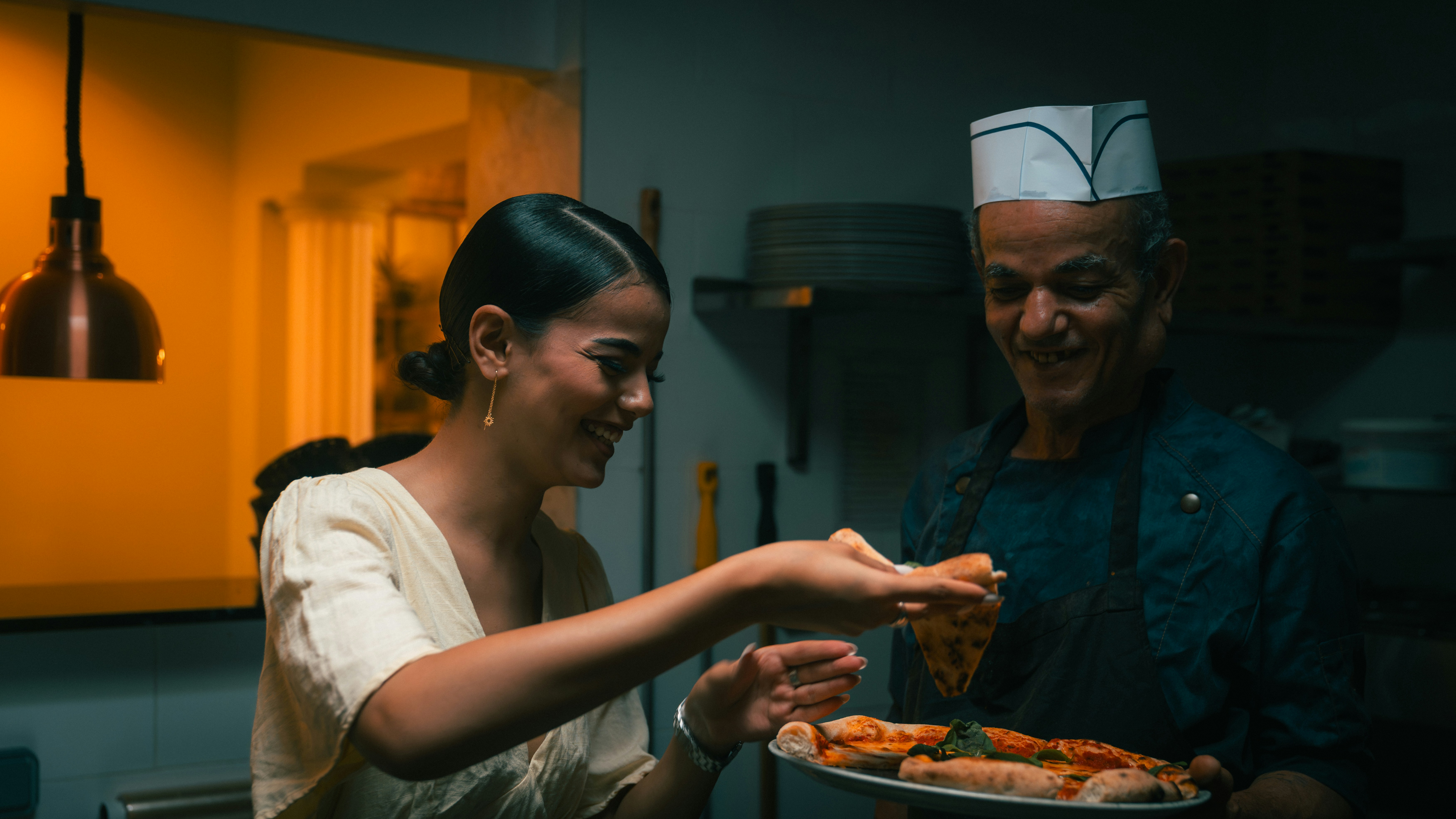 Diner taking a slice of pizza from a chef