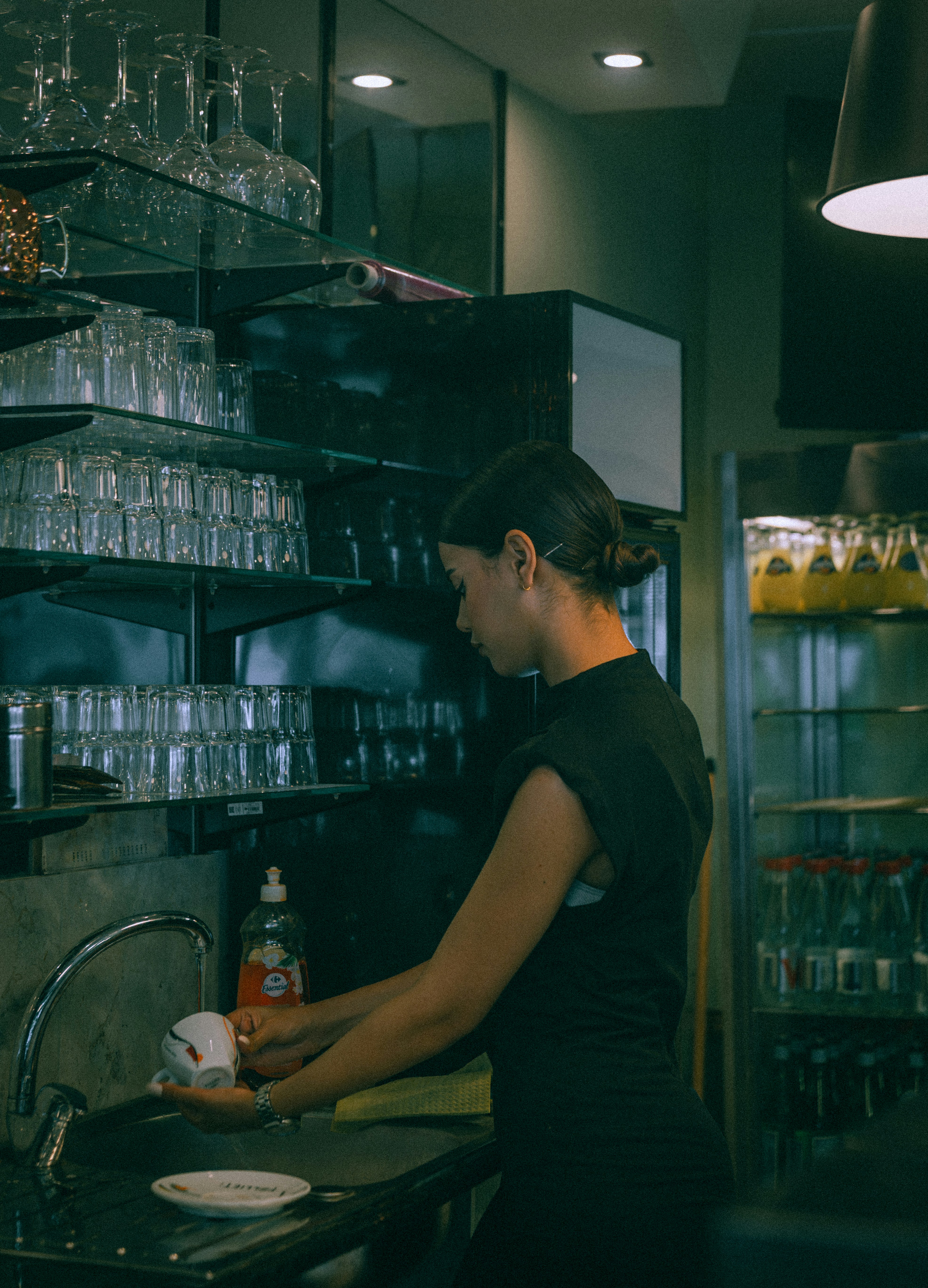 Back-of-house worker washing dishes at a café sink