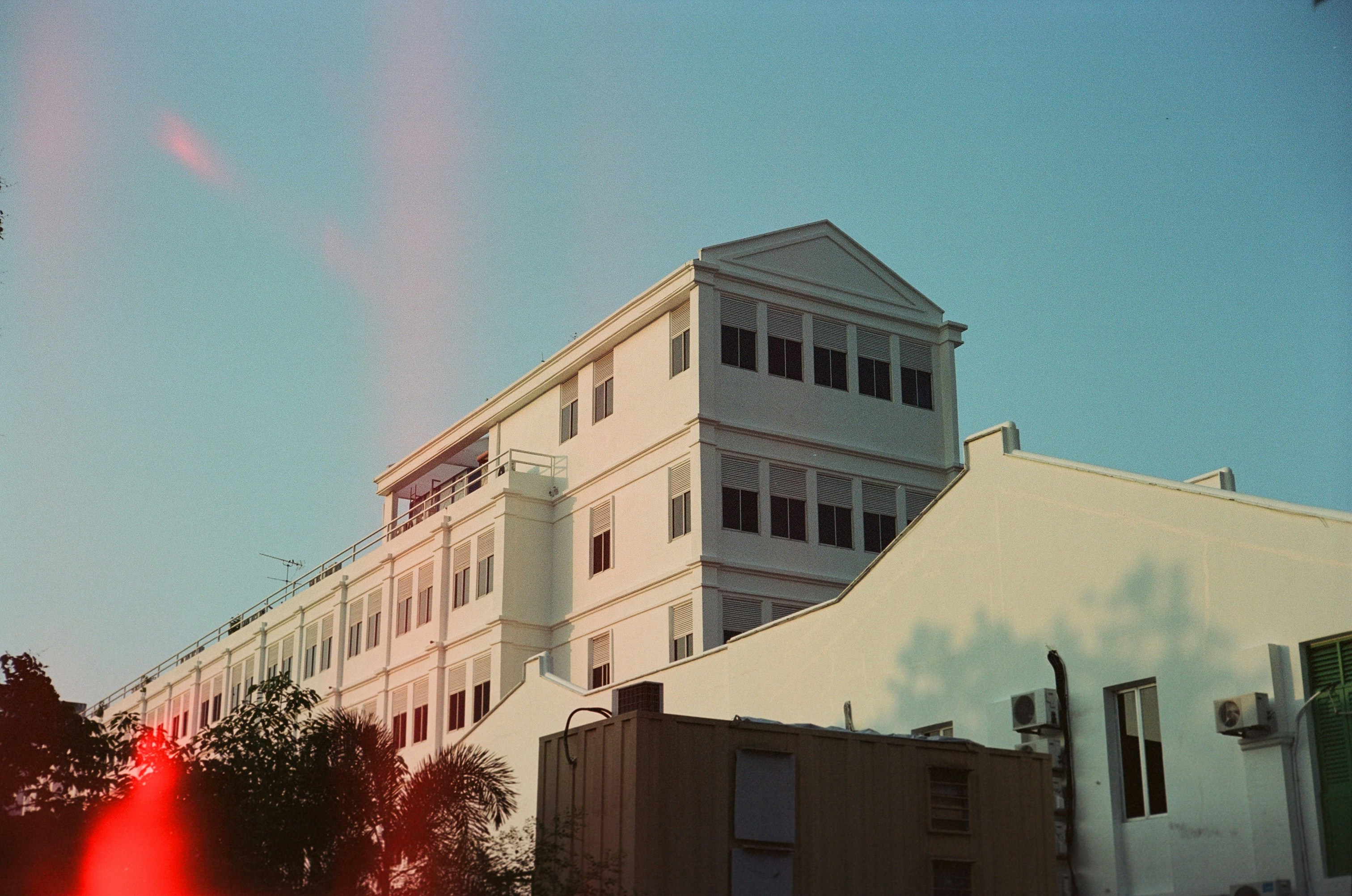 A white colonial style building with many windows under a clear blue sky
