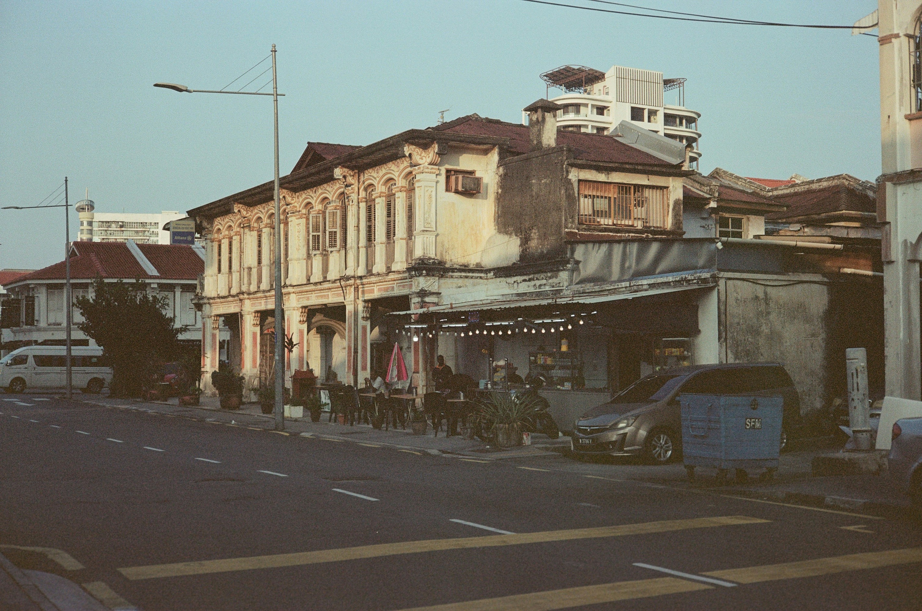 A historic shophouse with an outdoor cafe under string lights on a quiet street