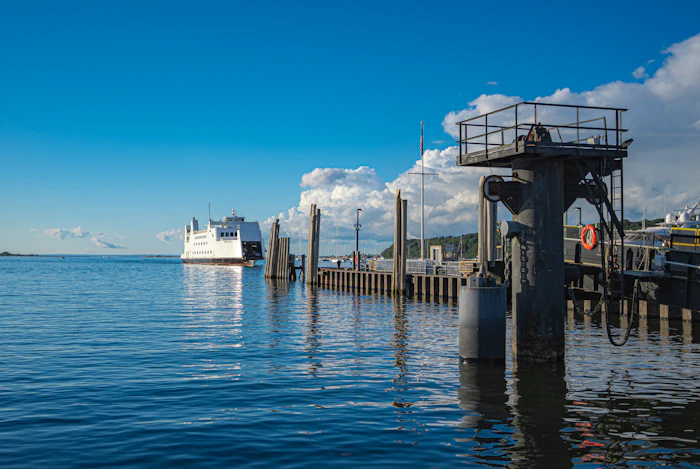 Ferry approaching a wooden pier on a calm blue bay