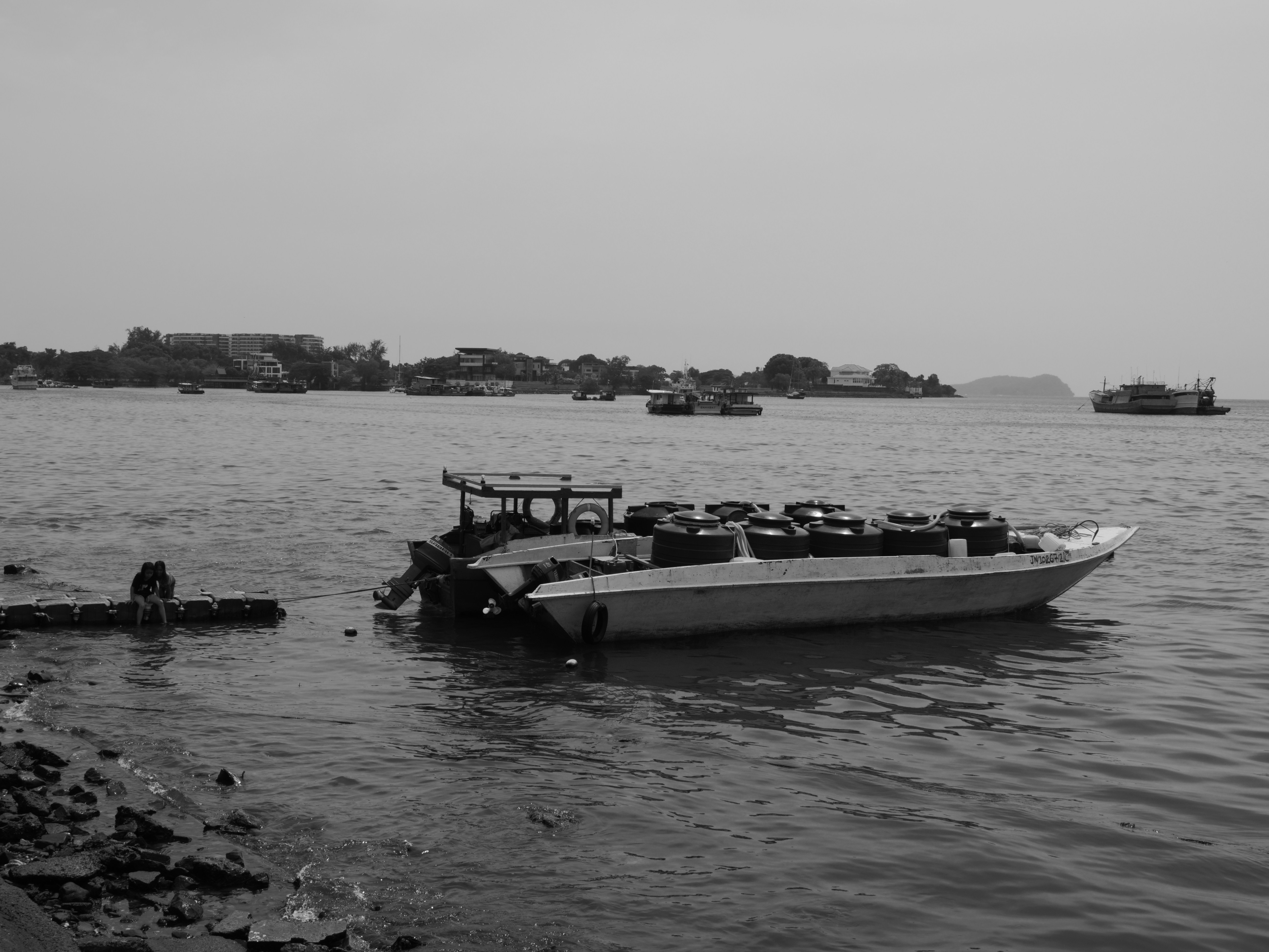 Un bateau transportant des réservoirs d’eau noire amarré près d’un quai flottant dans un port