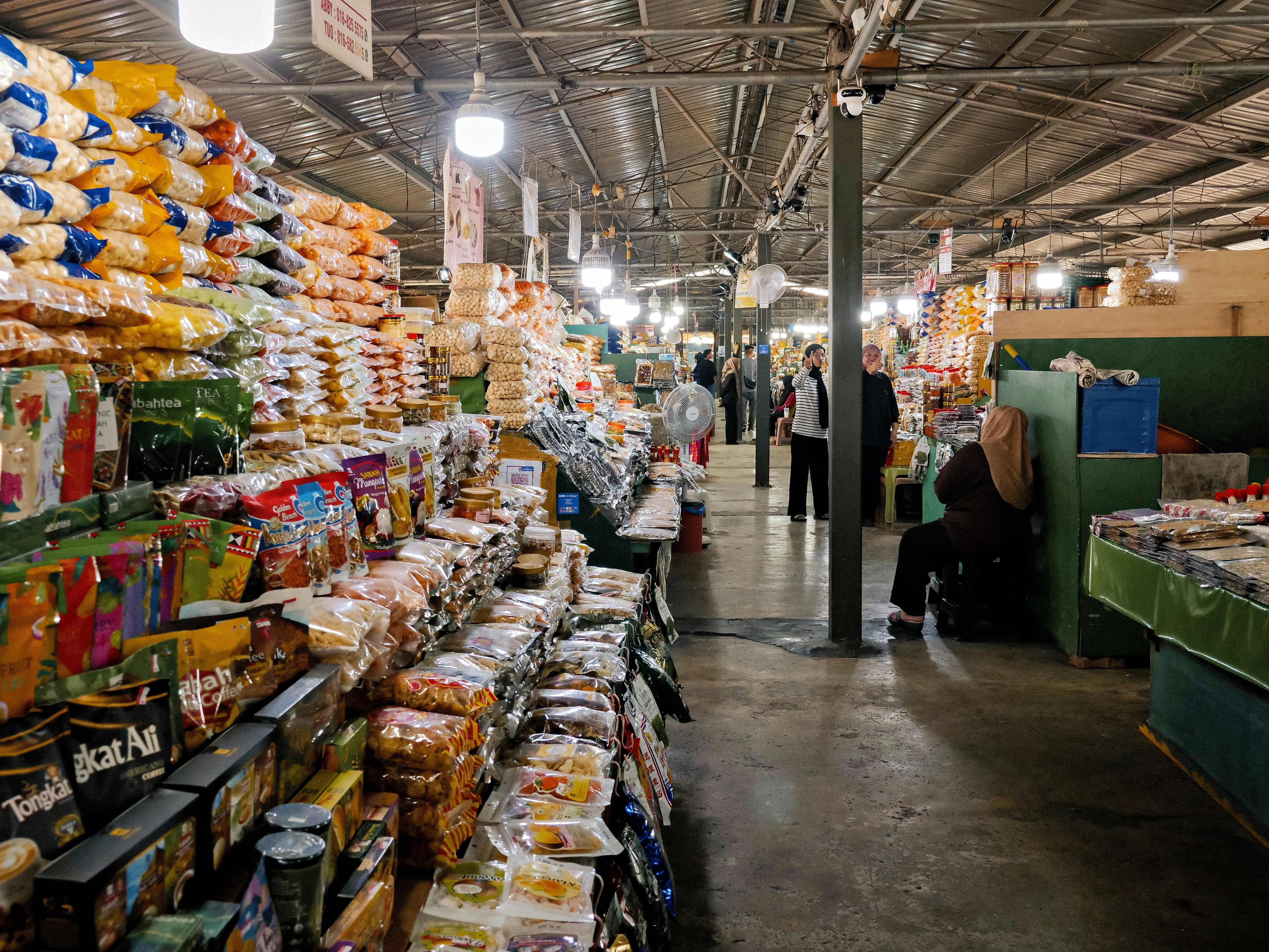 Des étagères remplies de snacks emballés et de café dans un marché intérieur bien éclairé