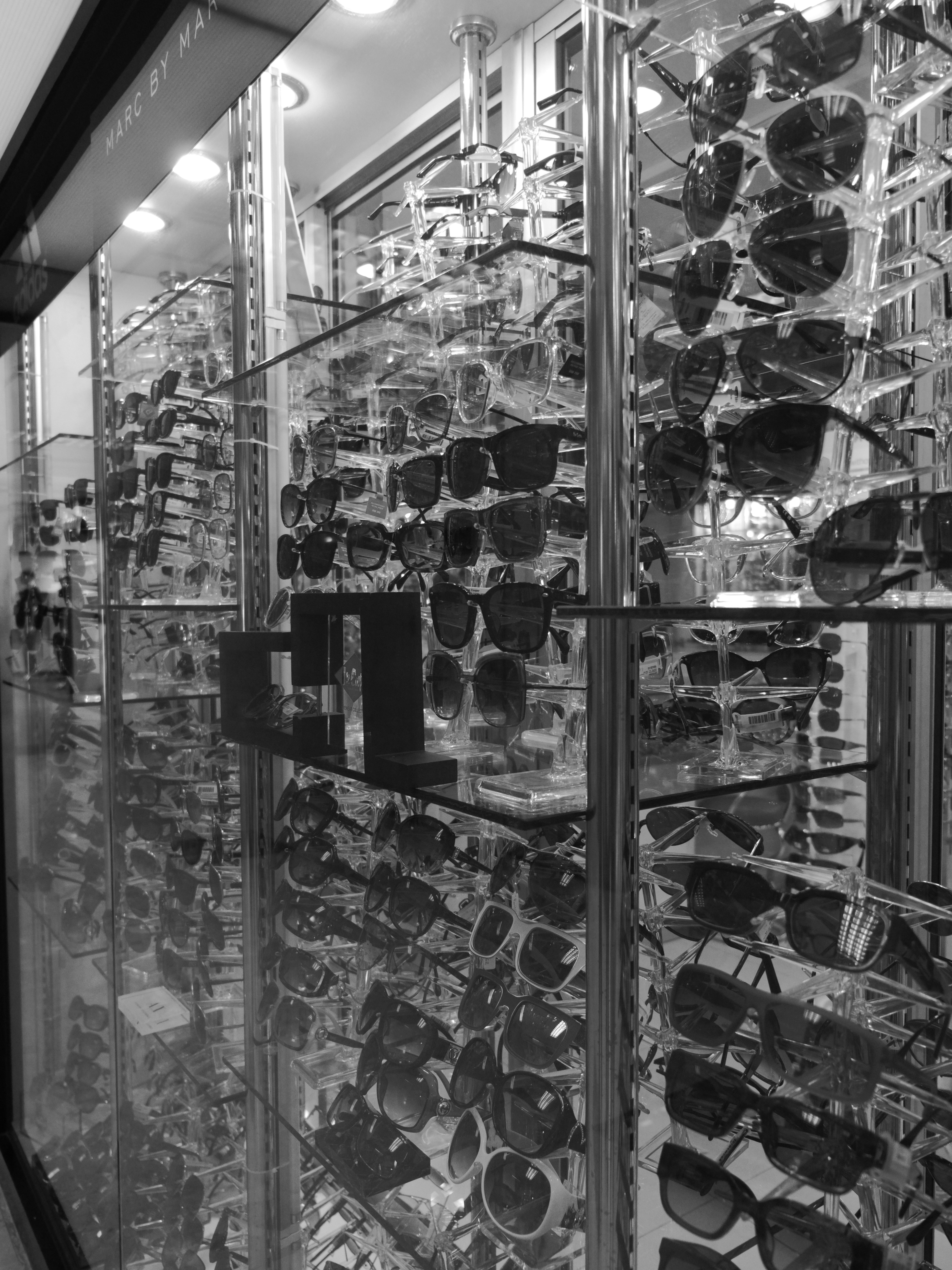 De nombreuses paires de lunettes de soleil exposées sur des étagères en verre à étages dans un magasin