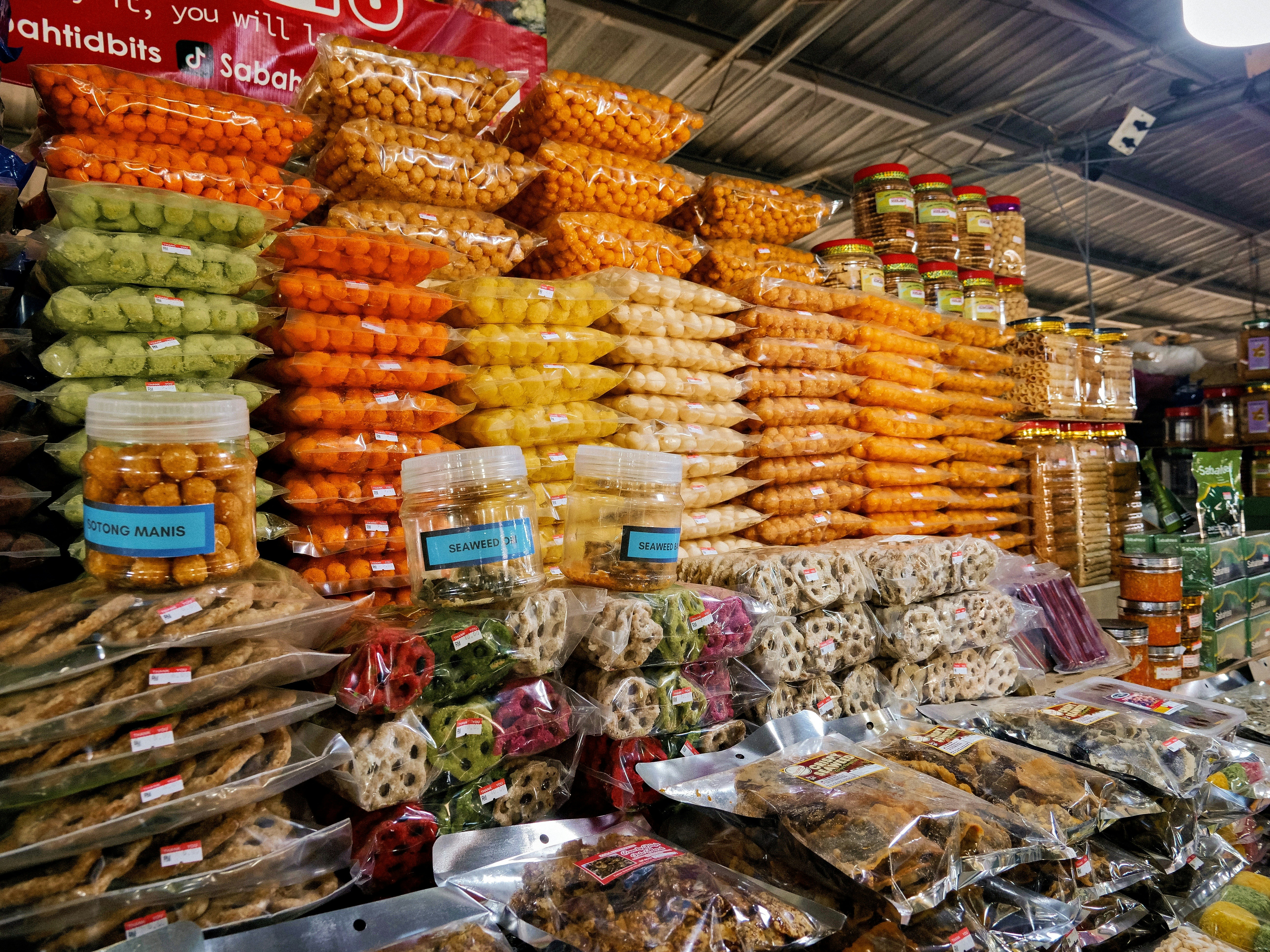 Des piles de snacks colorés dans des sacs plastiques et des bocaux à un stand de marché