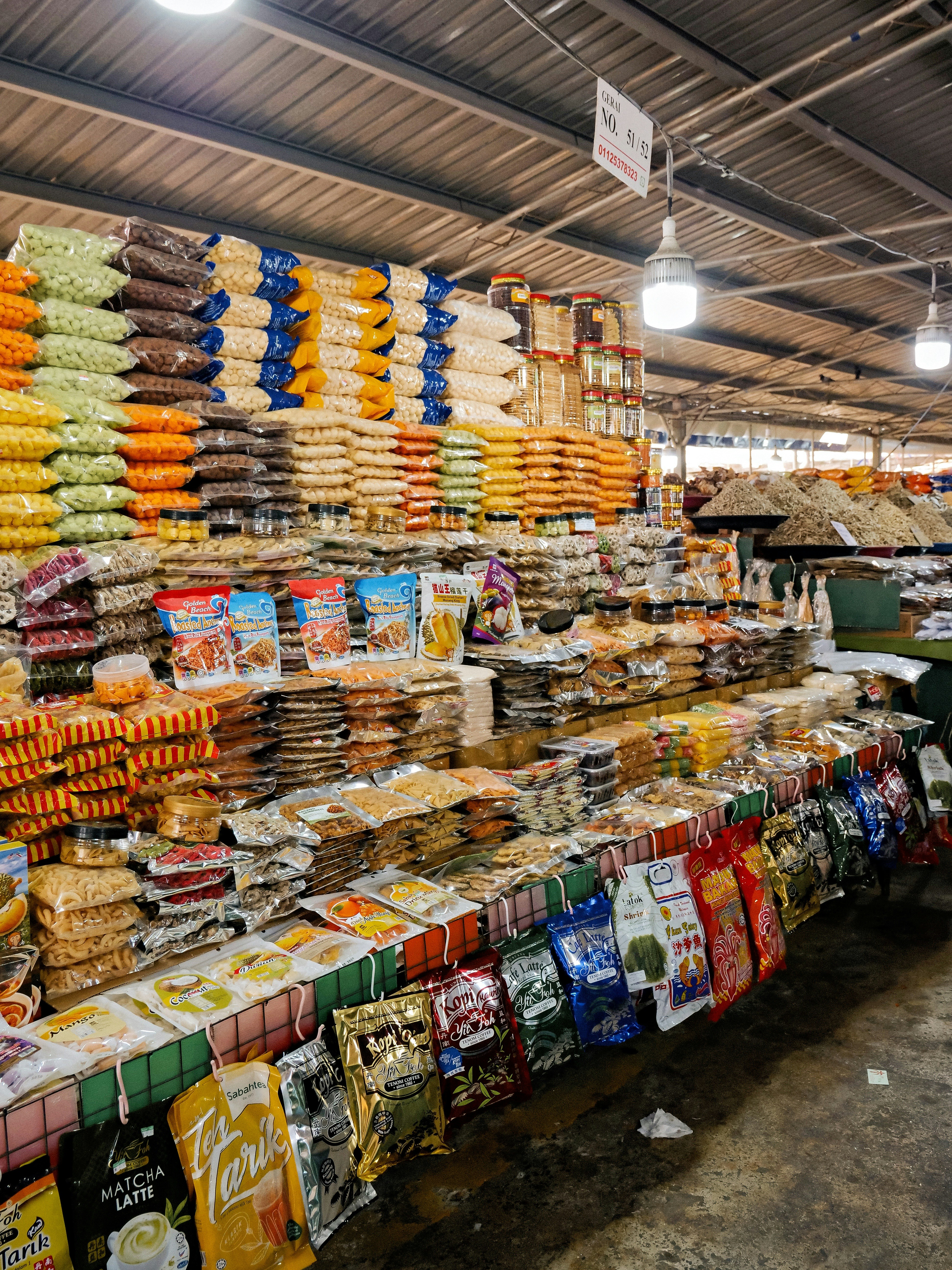 Un stand de marché avec des étagères remplies de snacks colorés emballés et de produits secs