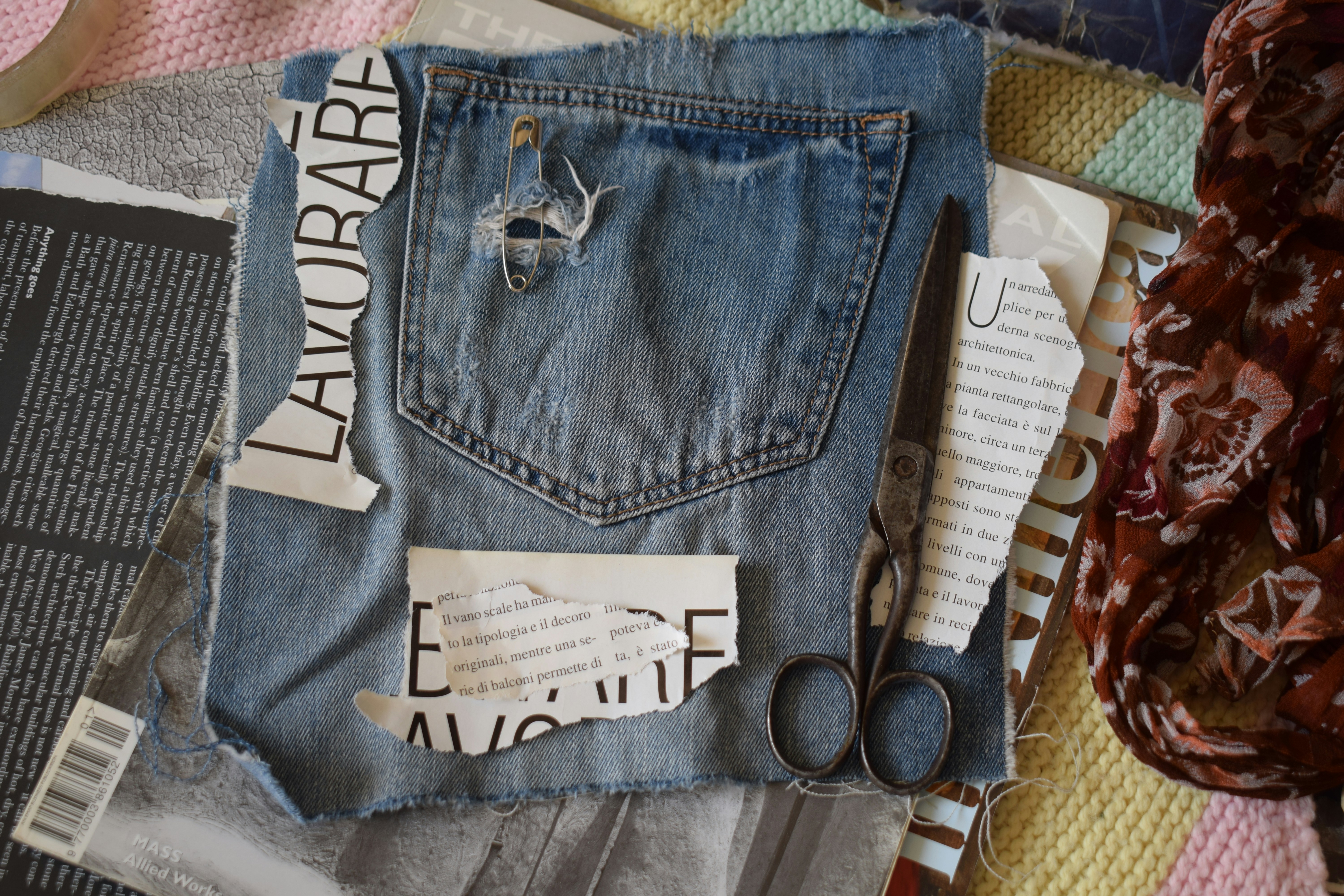 A denim pocket with a safety pin, scissors, and torn paper scraps