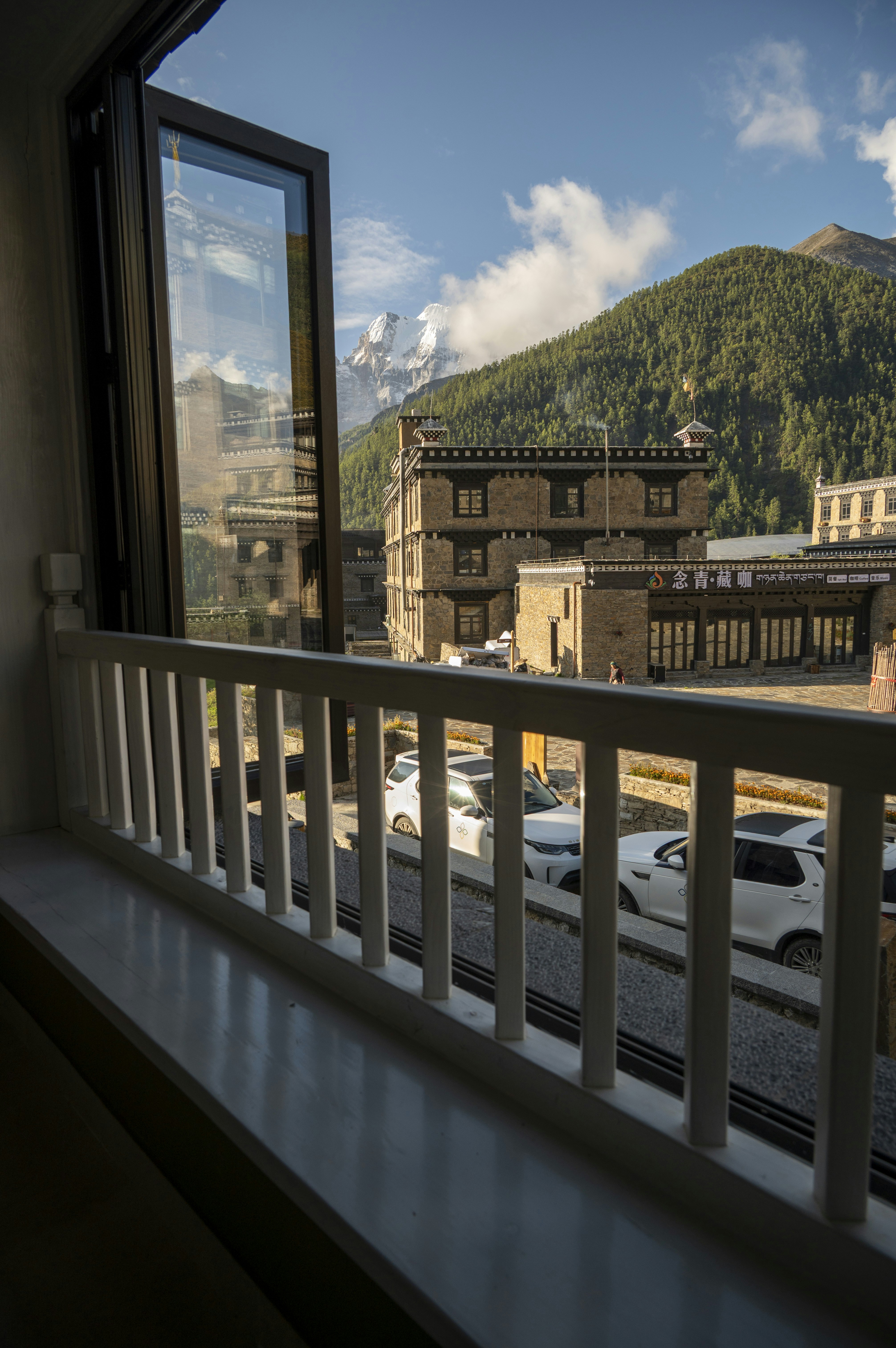 A view from a window of stone buildings and snow-capped mountains in Tibet