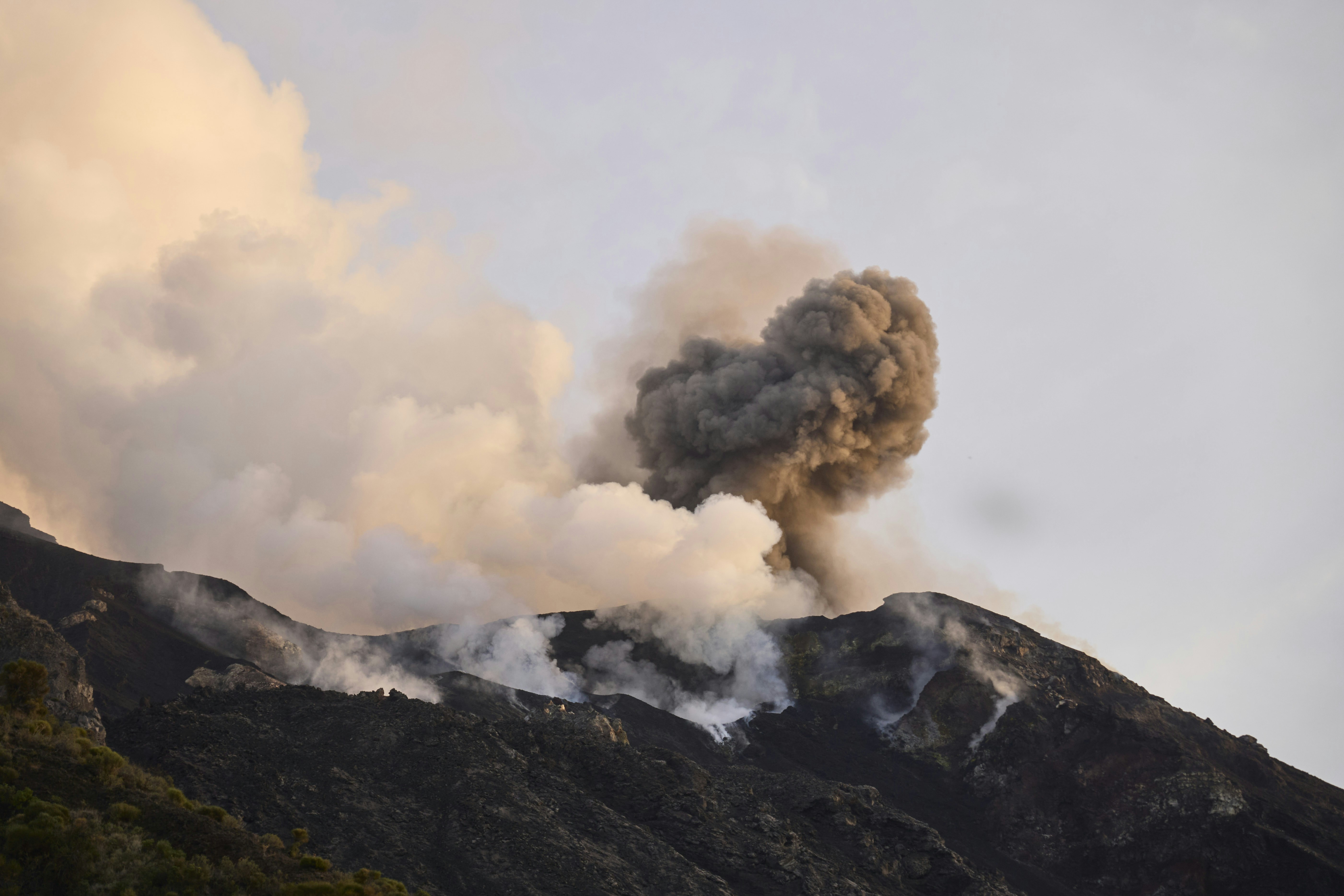 A volcanic eruption with dark ash and white steam rising from a mountain