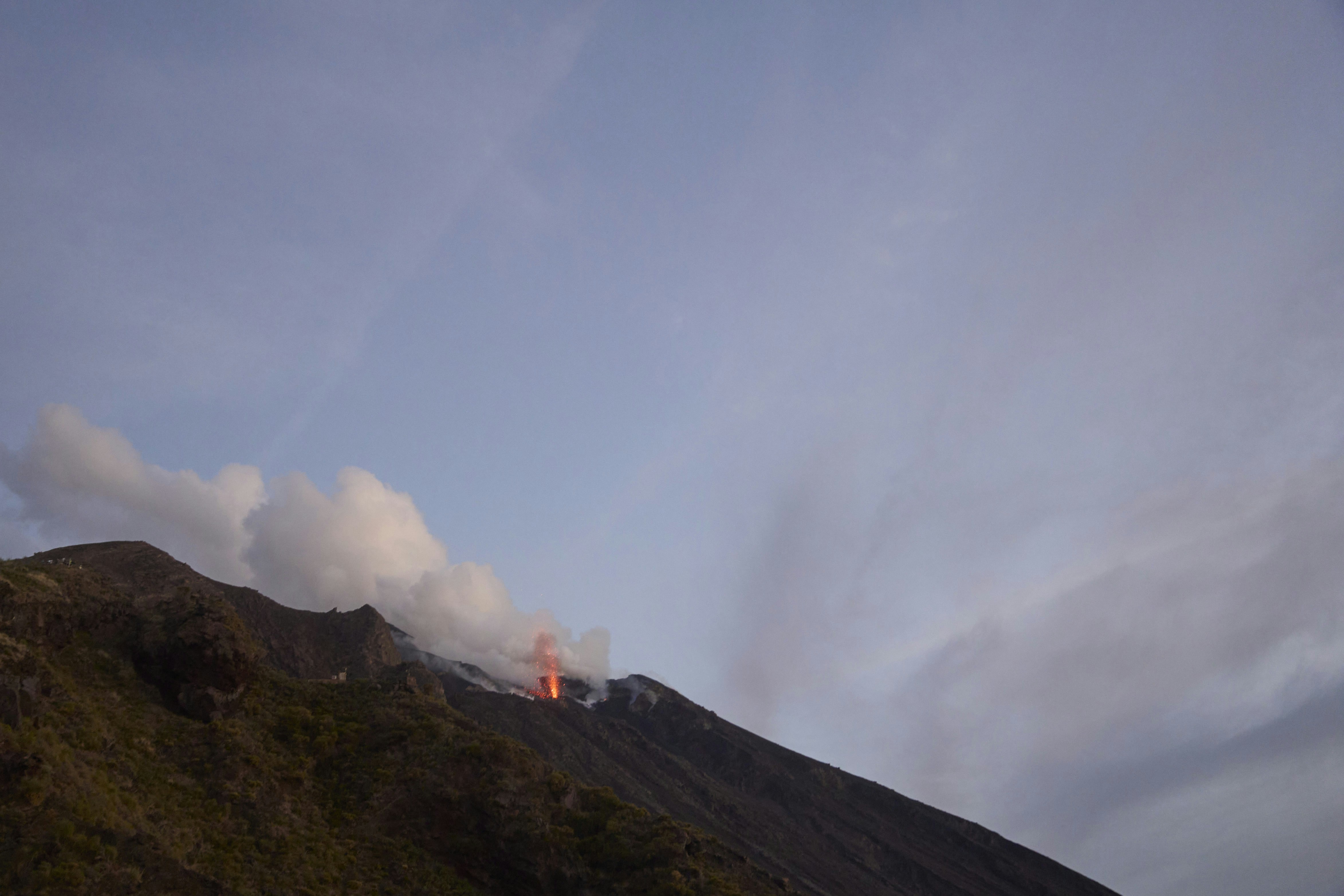 A volcanic eruption with glowing lava and smoke on a dark mountain slope