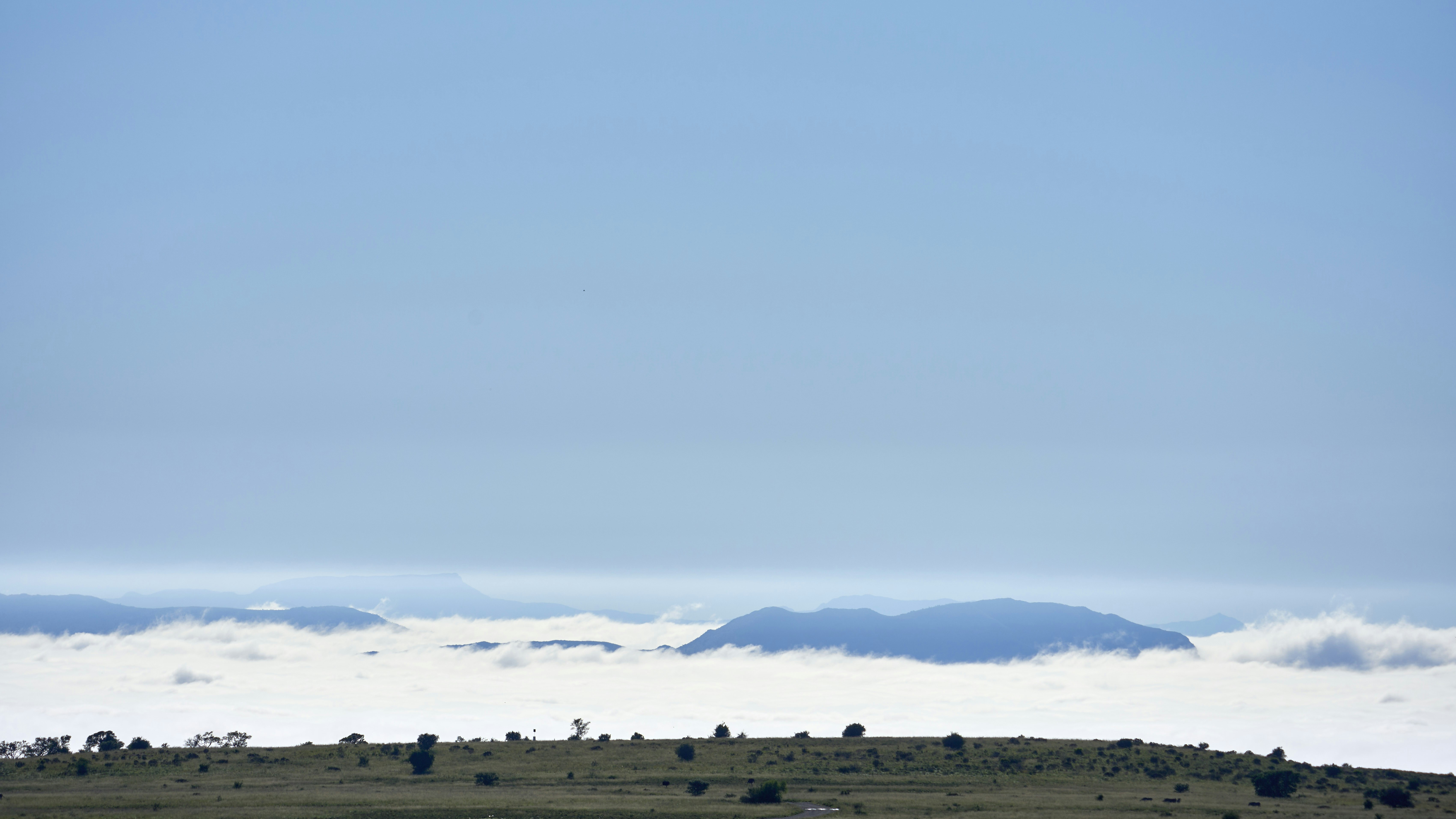 Distant blue mountains rising above a thick layer of low clouds