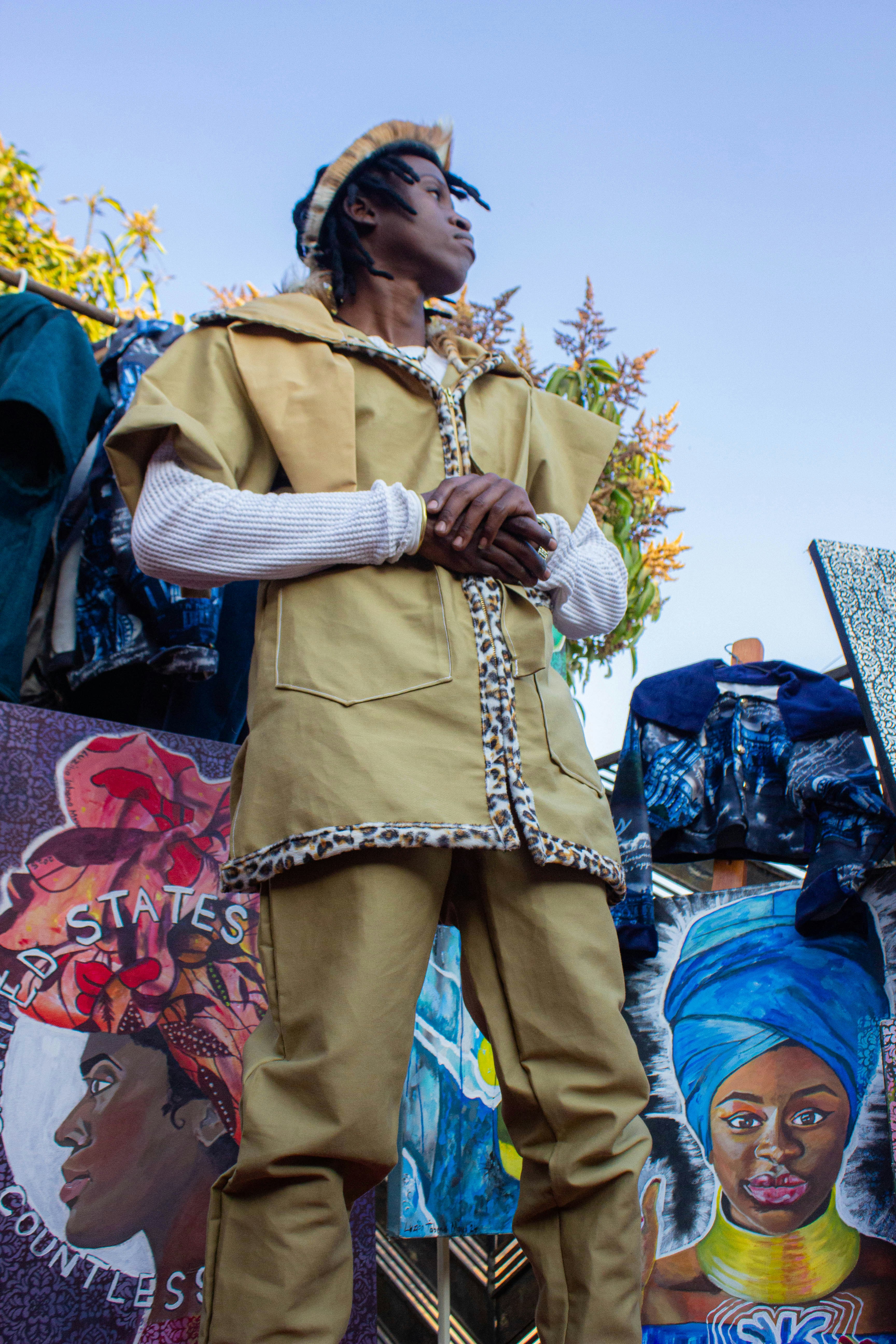 A person in a tan jacket and pants standing among colorful paintings