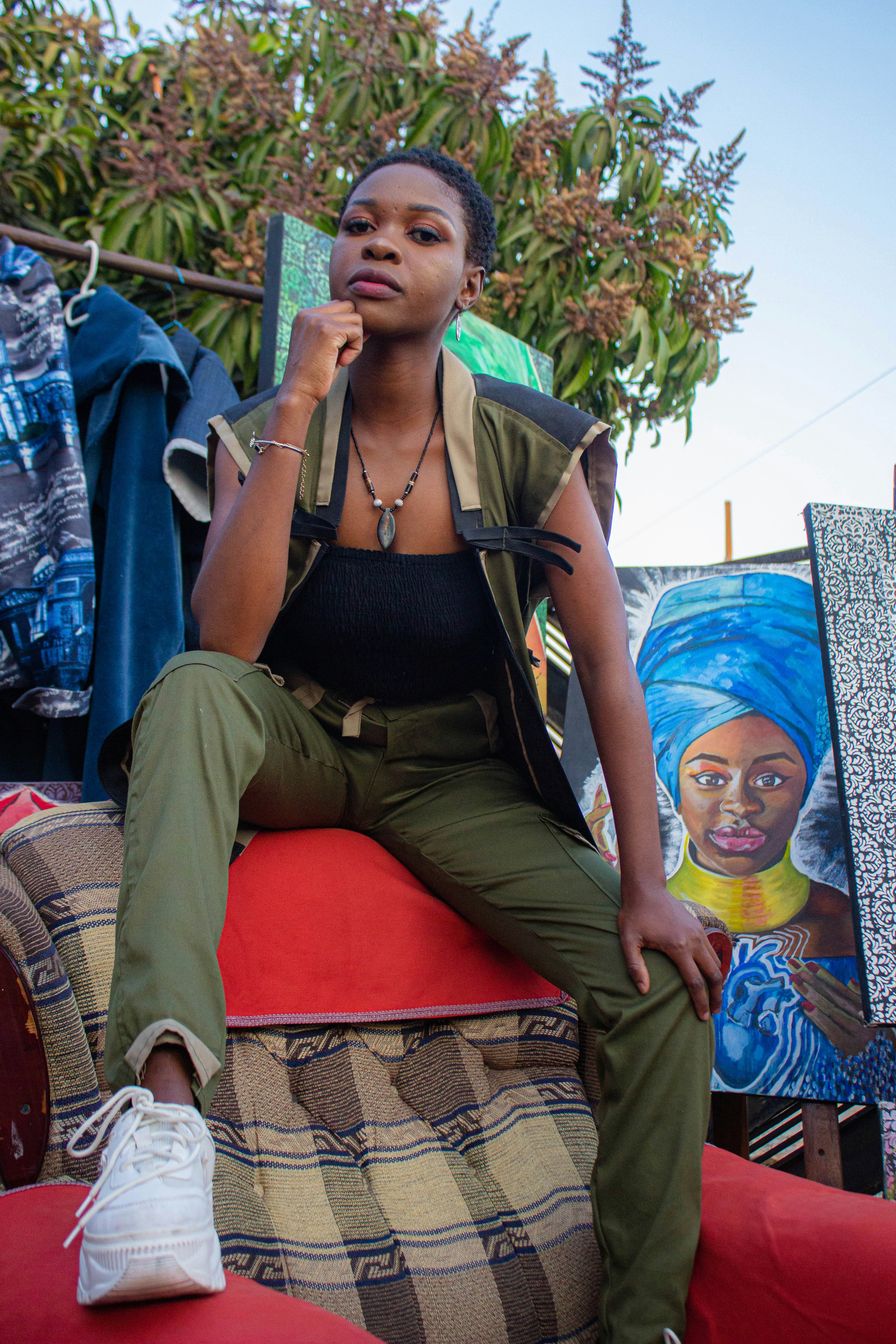 A person in olive green pants and vest sitting on a patterned armchair