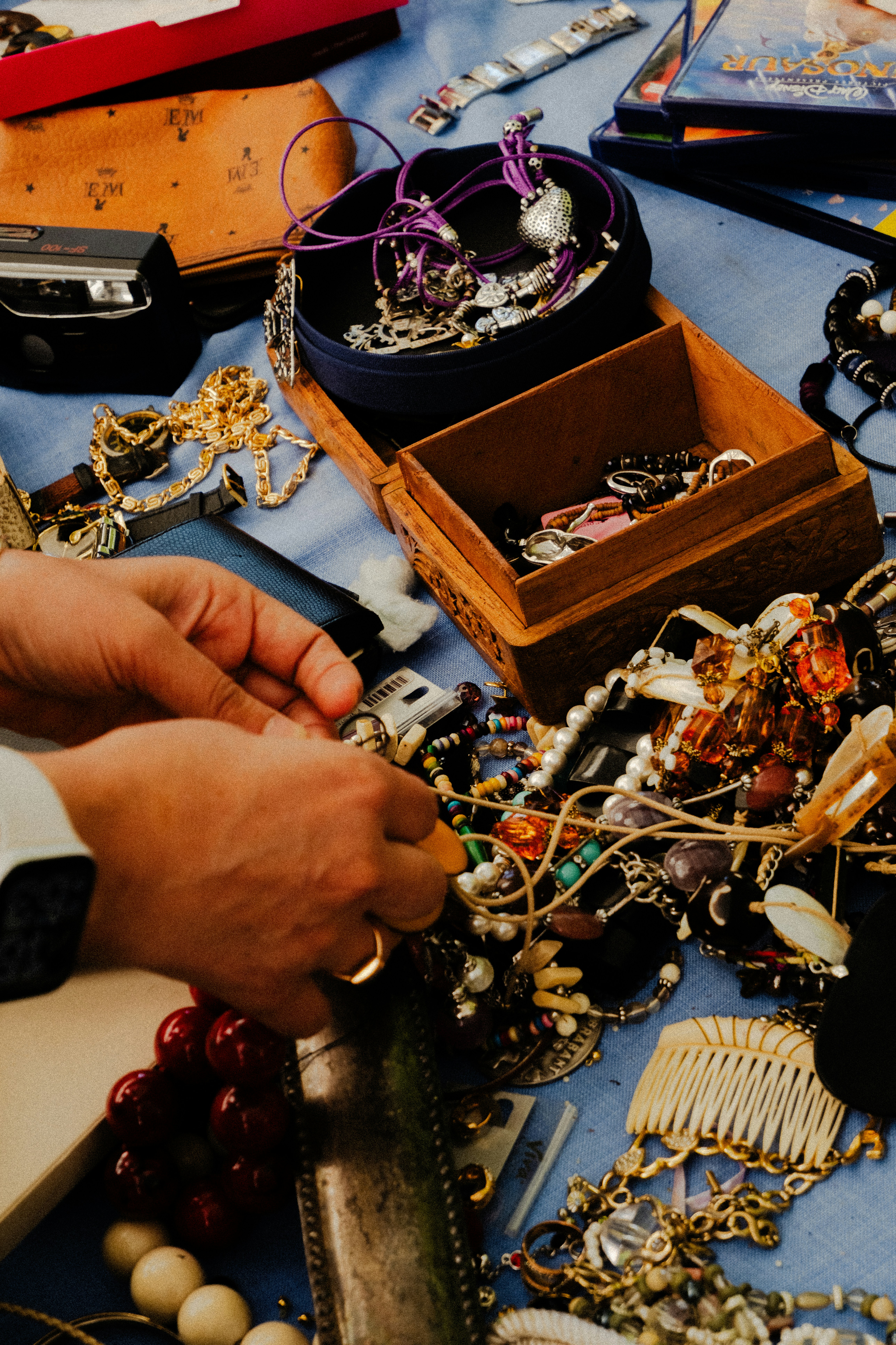 A person sorting through a collection of vintage jewelry on a blue cloth