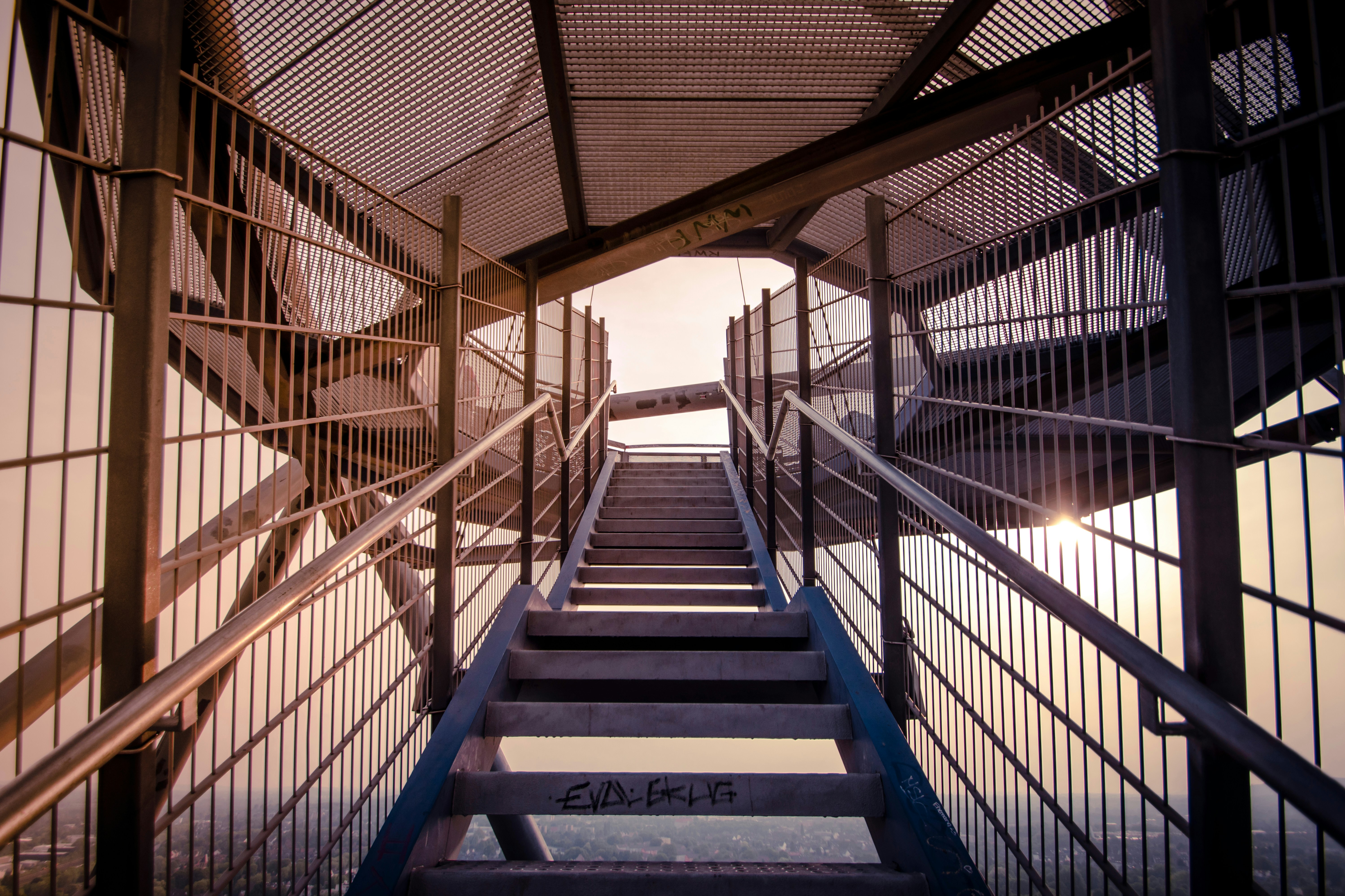 Metal stairs ascending inside a tall observation tower at golden hour