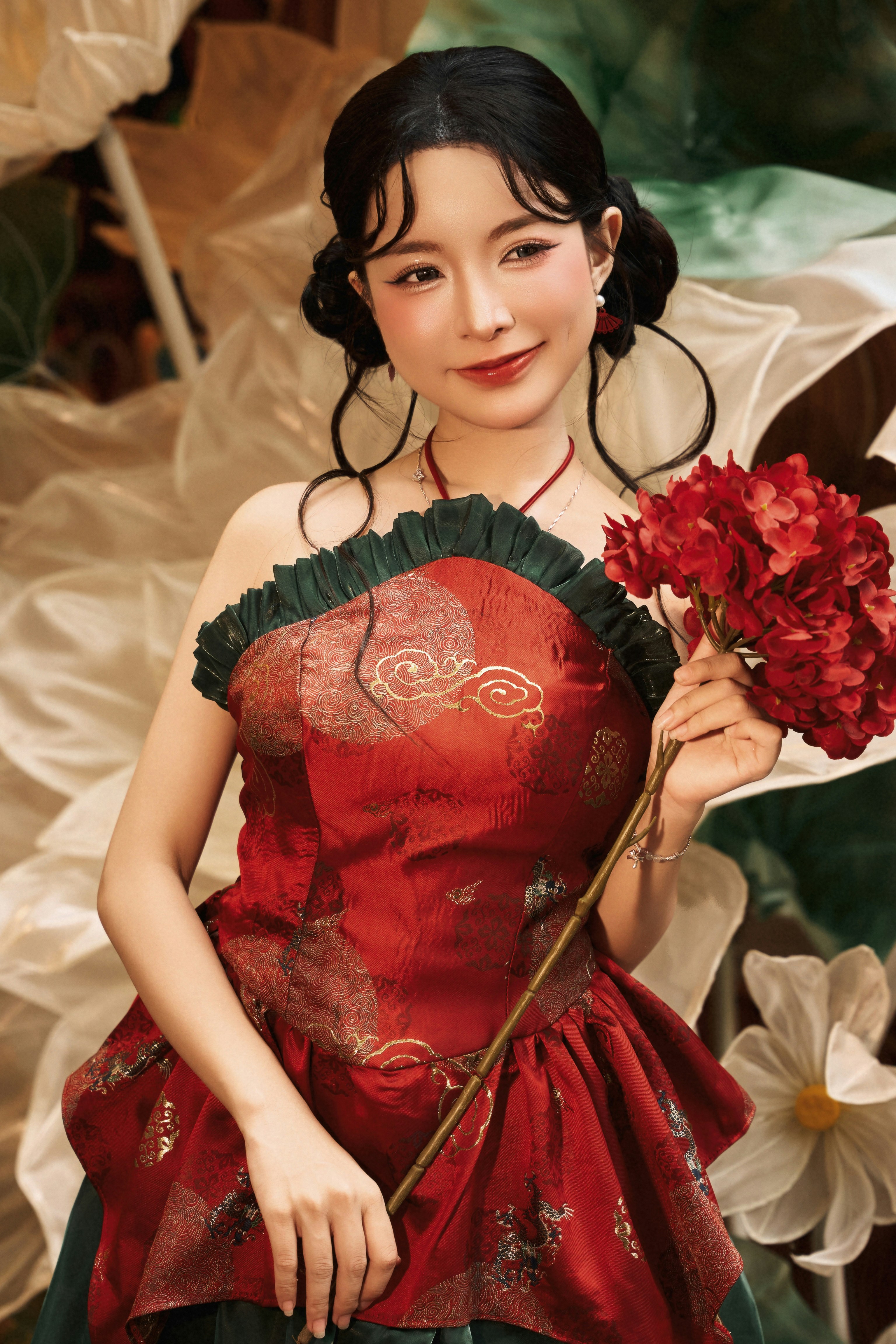 A woman in a red patterned dress holding a cluster of red flowers