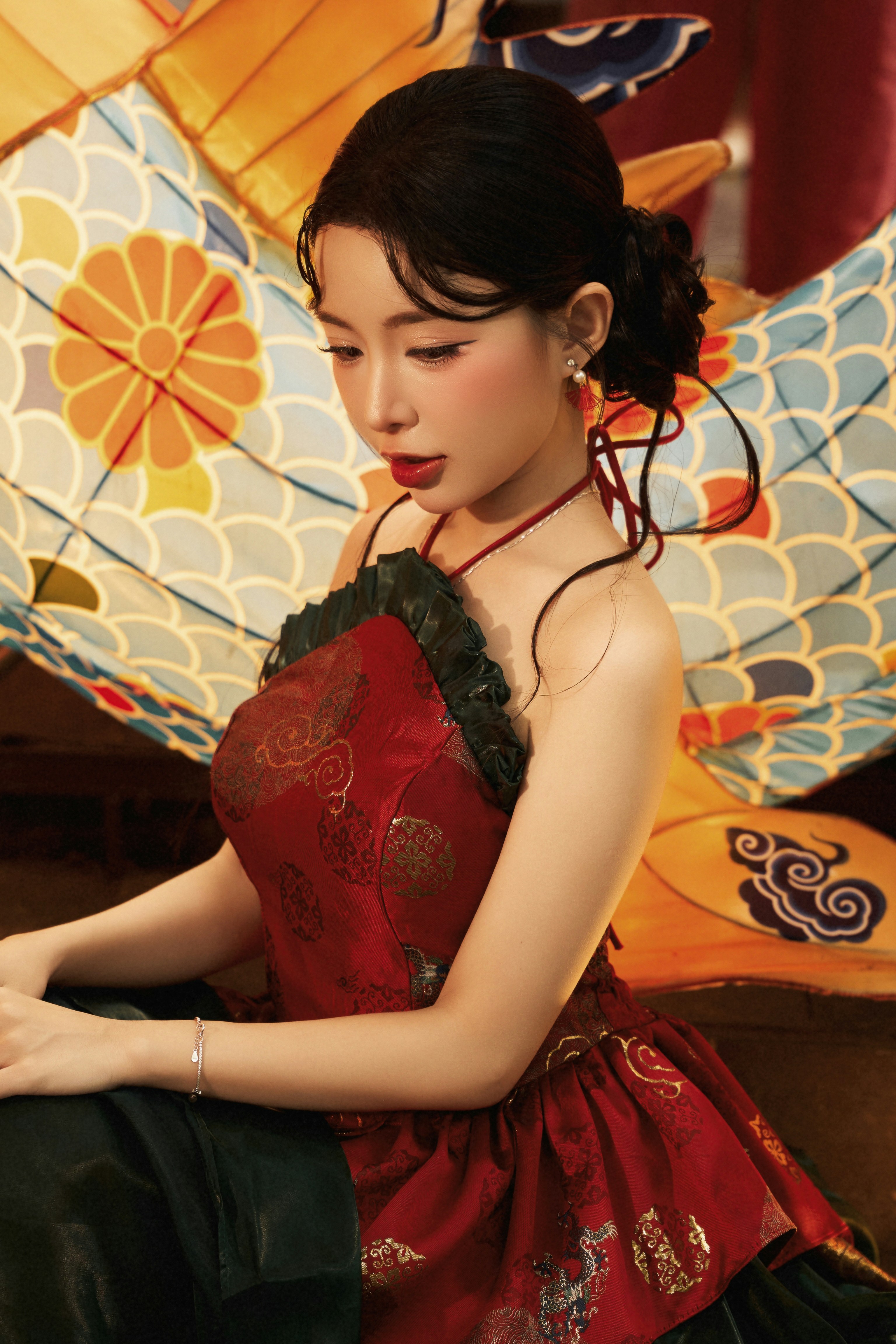 A woman in a red patterned halter dress with a large decorative fan