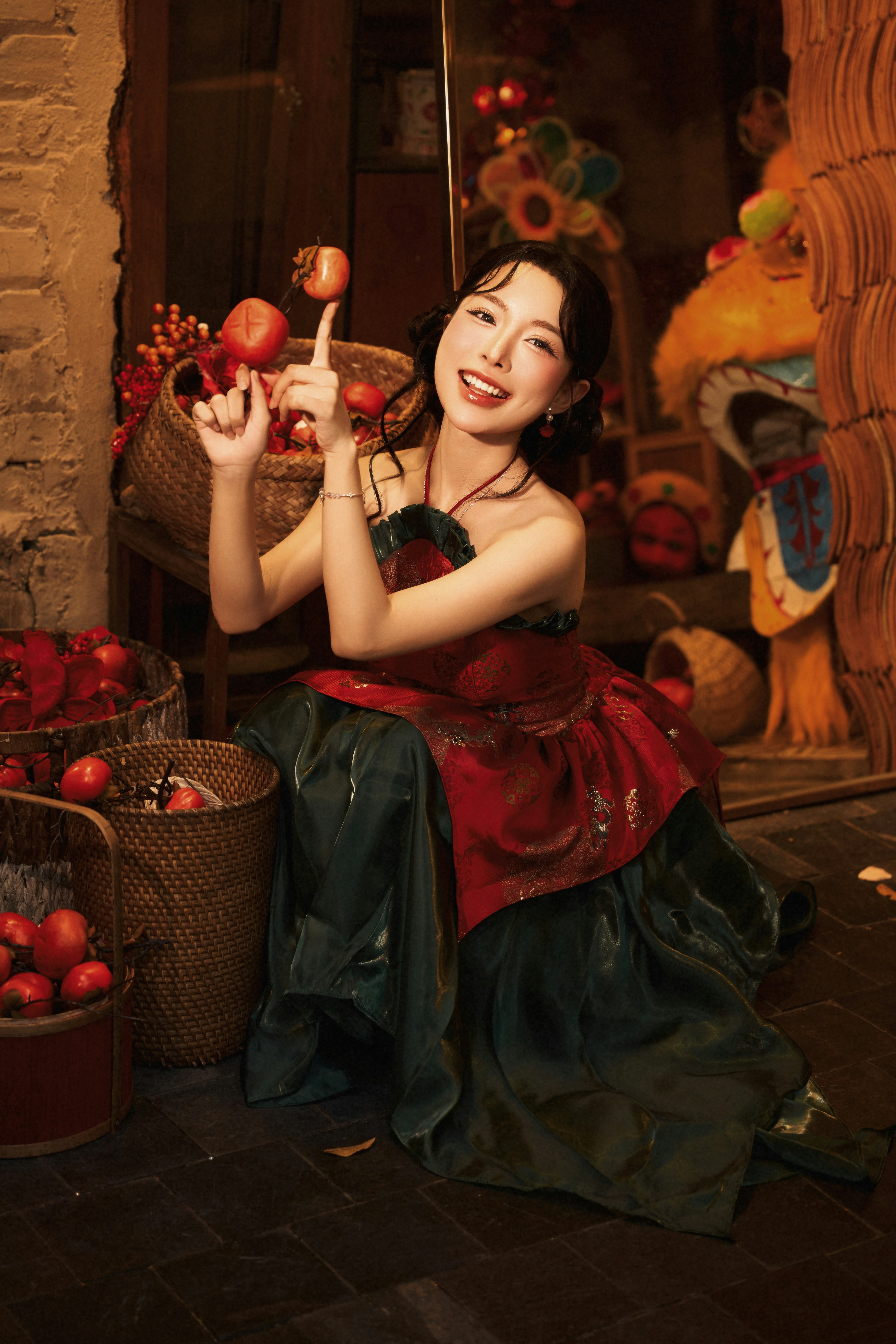 A woman in a red and green dress crouching beside baskets of persimmons