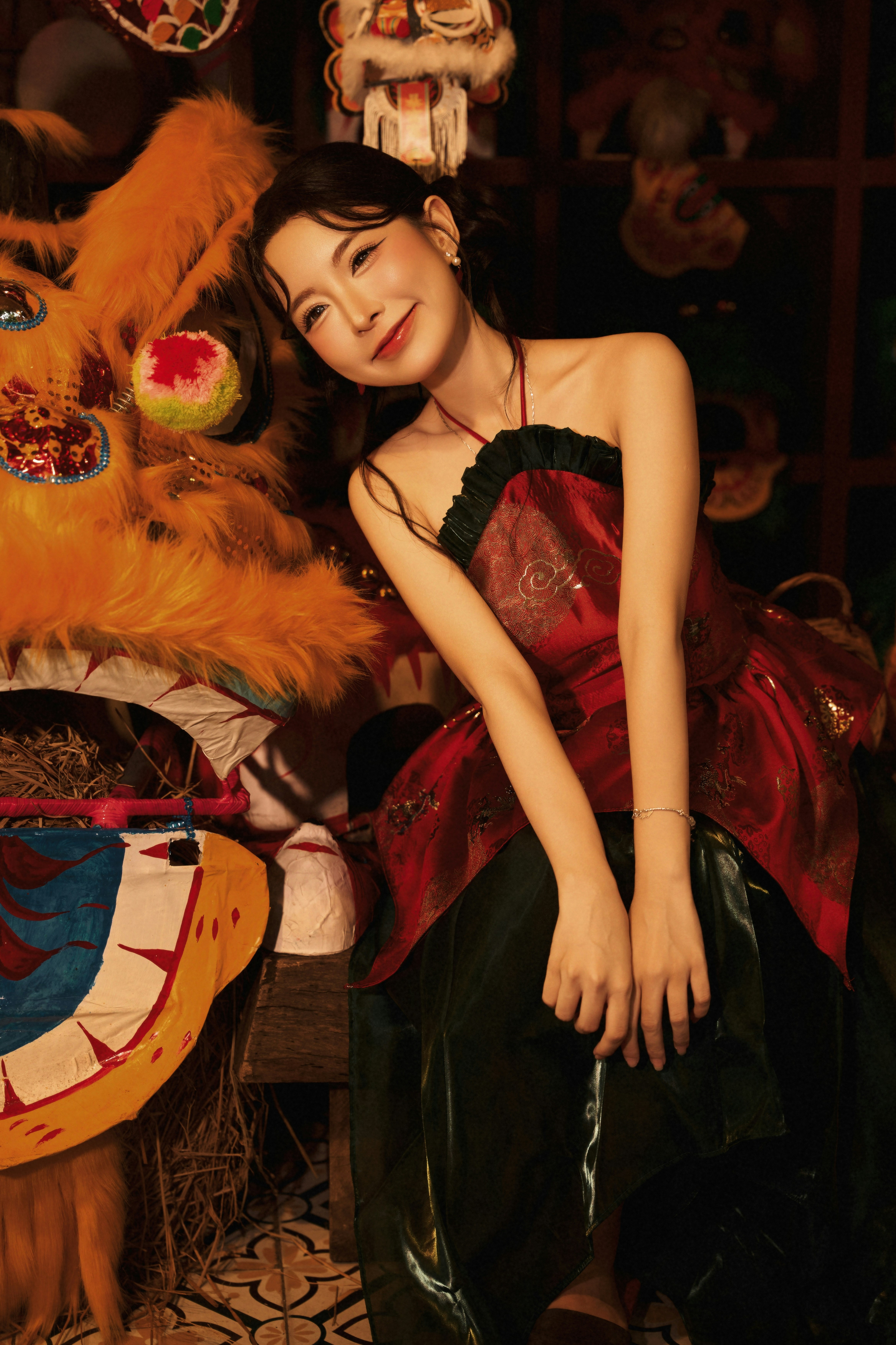 A woman in a red and green dress beside a lion dance costume