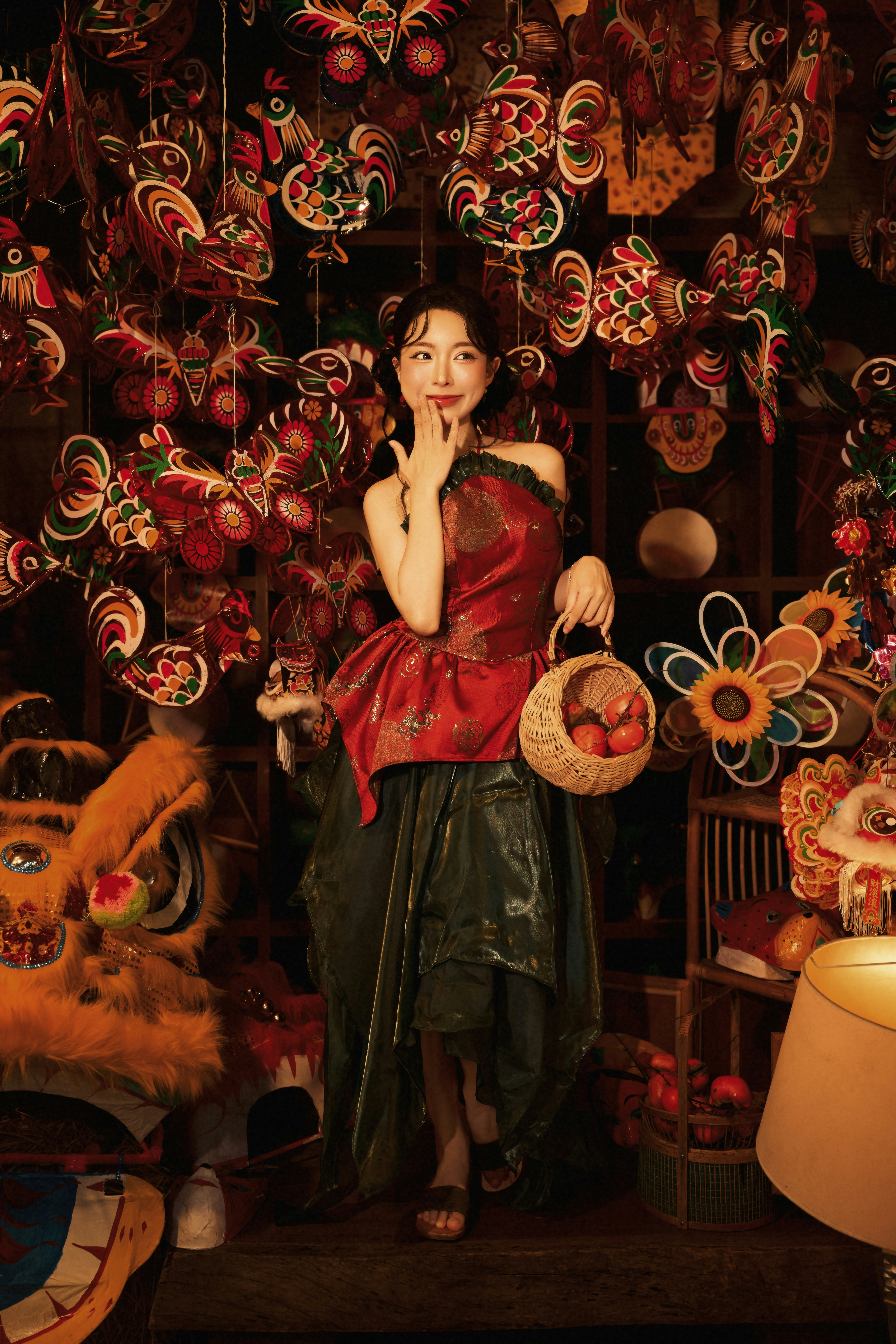 A woman in a red top and green skirt holding a basket of fruit