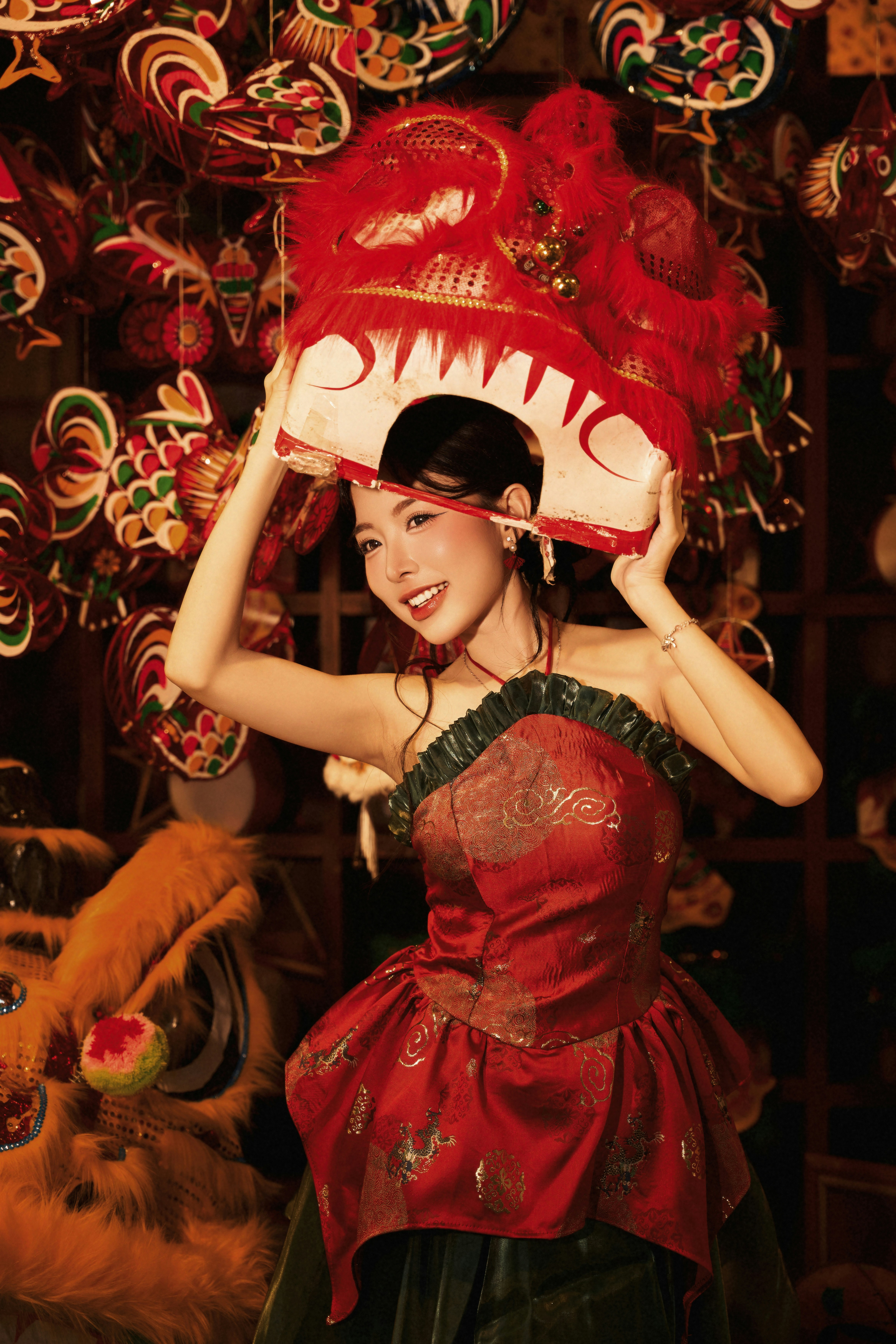 A woman in a red dress holding a lion dance mask overhead