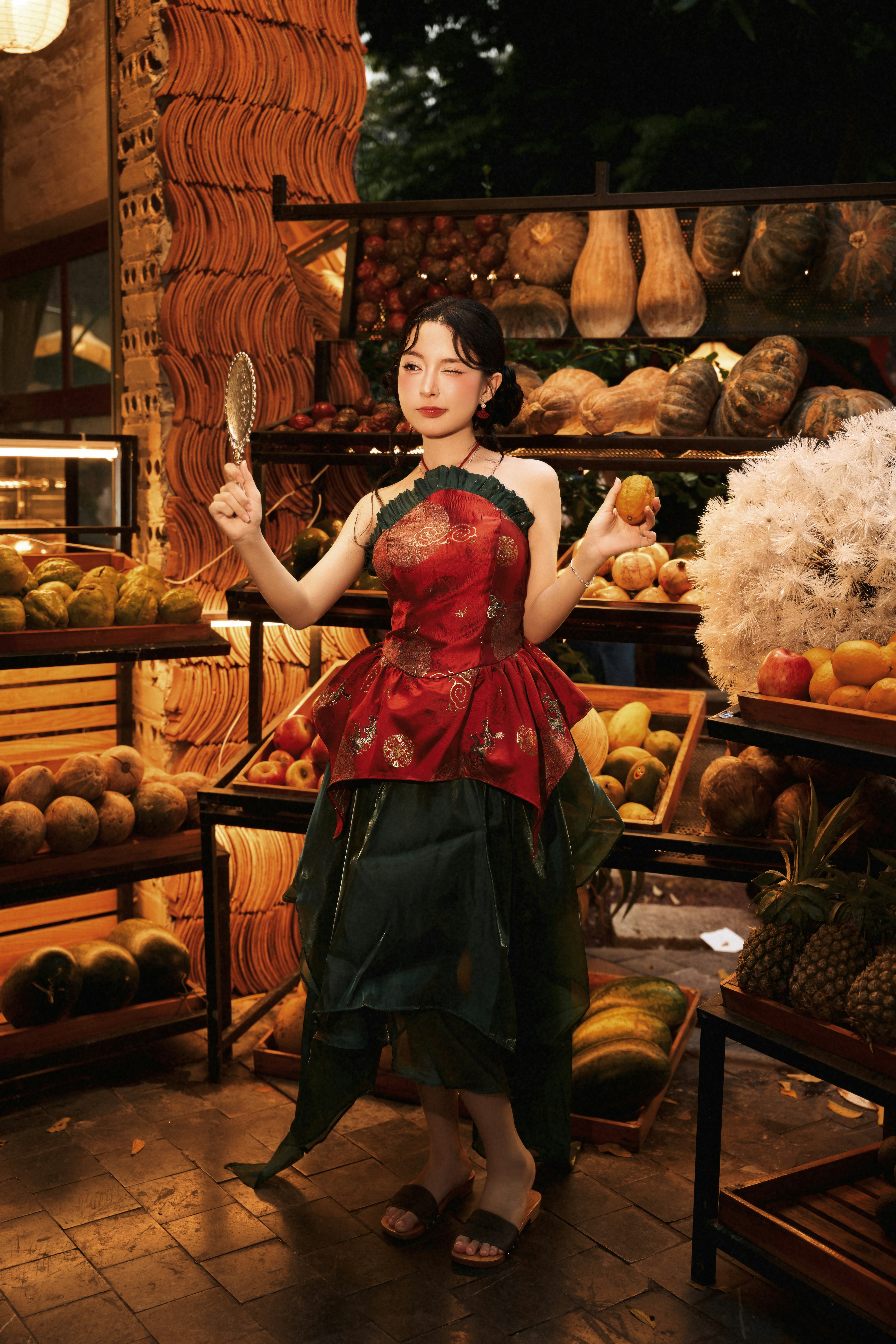 A woman in a red and green dress holding a mirror and fruit