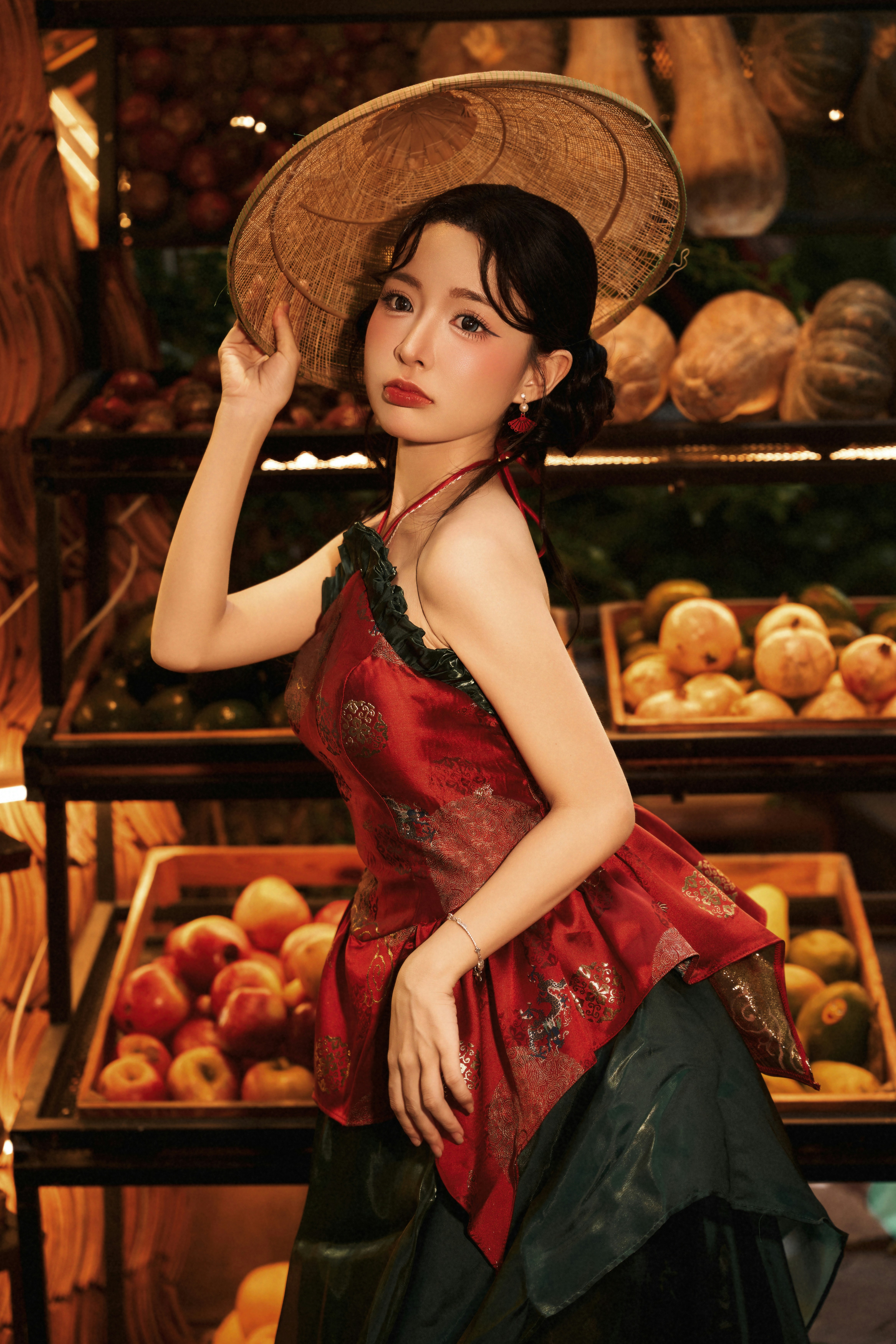 A woman in a red patterned top and conical hat in a fruit market