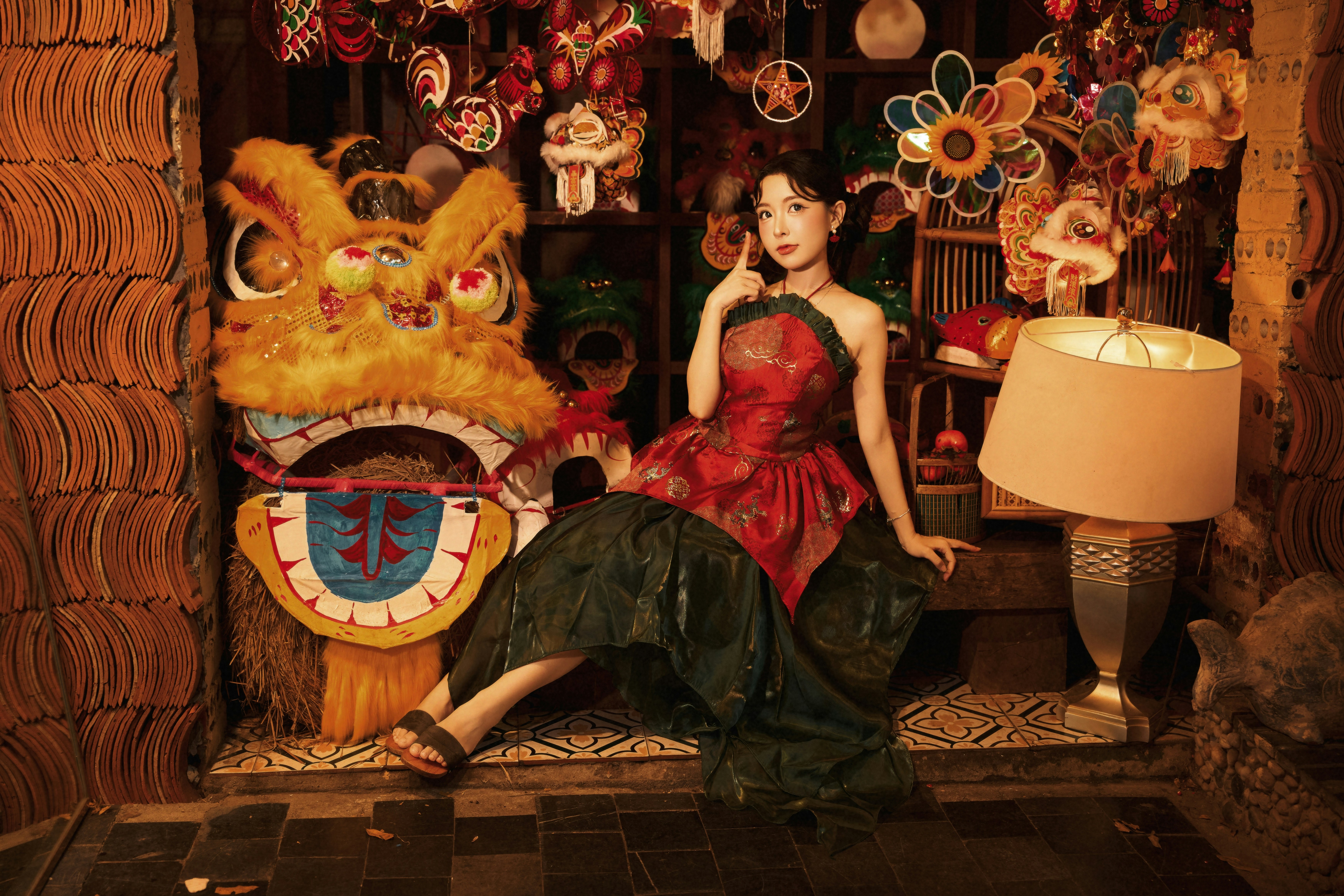 A woman in a red and green dress beside a lion dance head