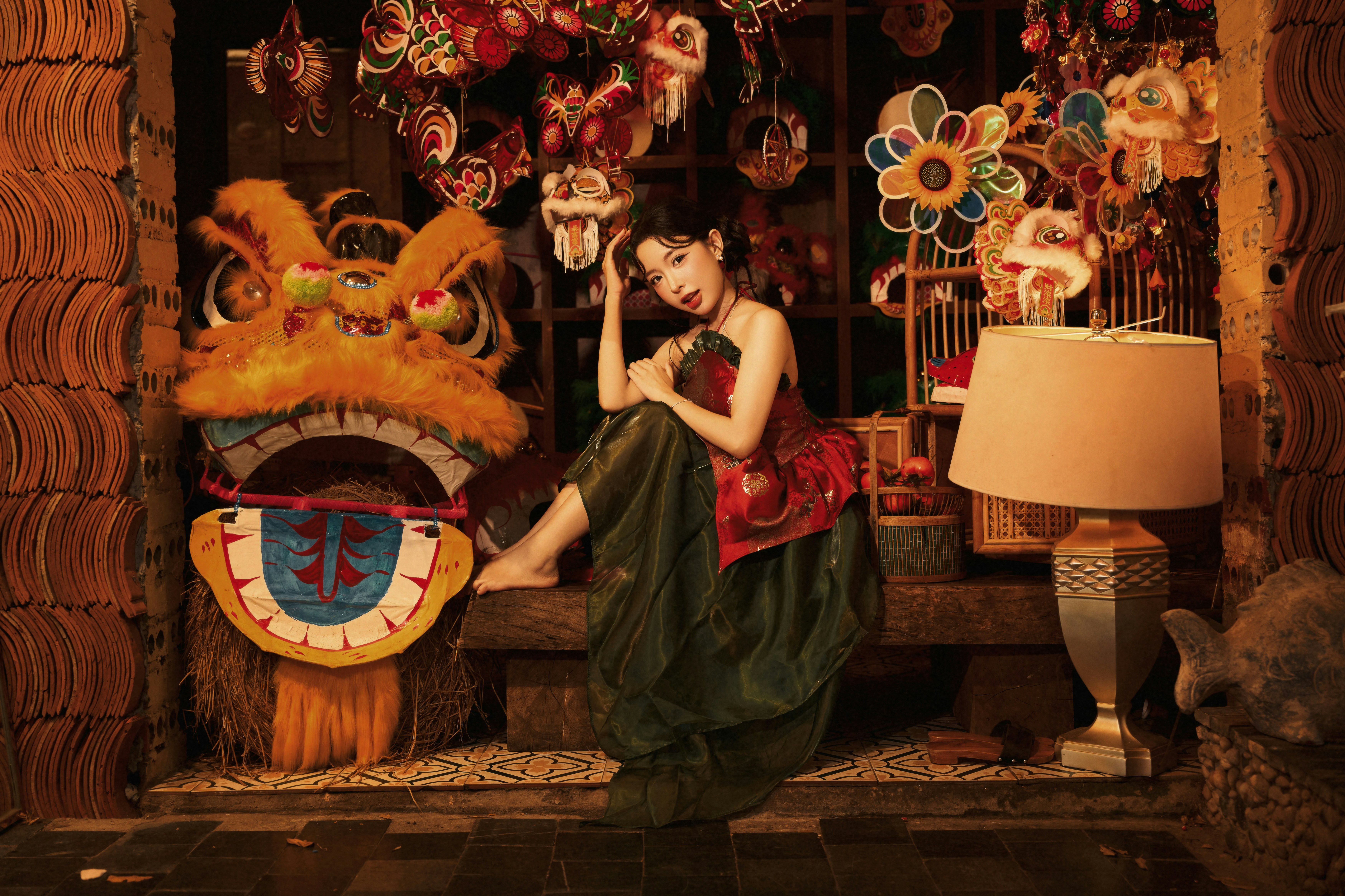 A woman in a red and green dress beside a lion dance head
