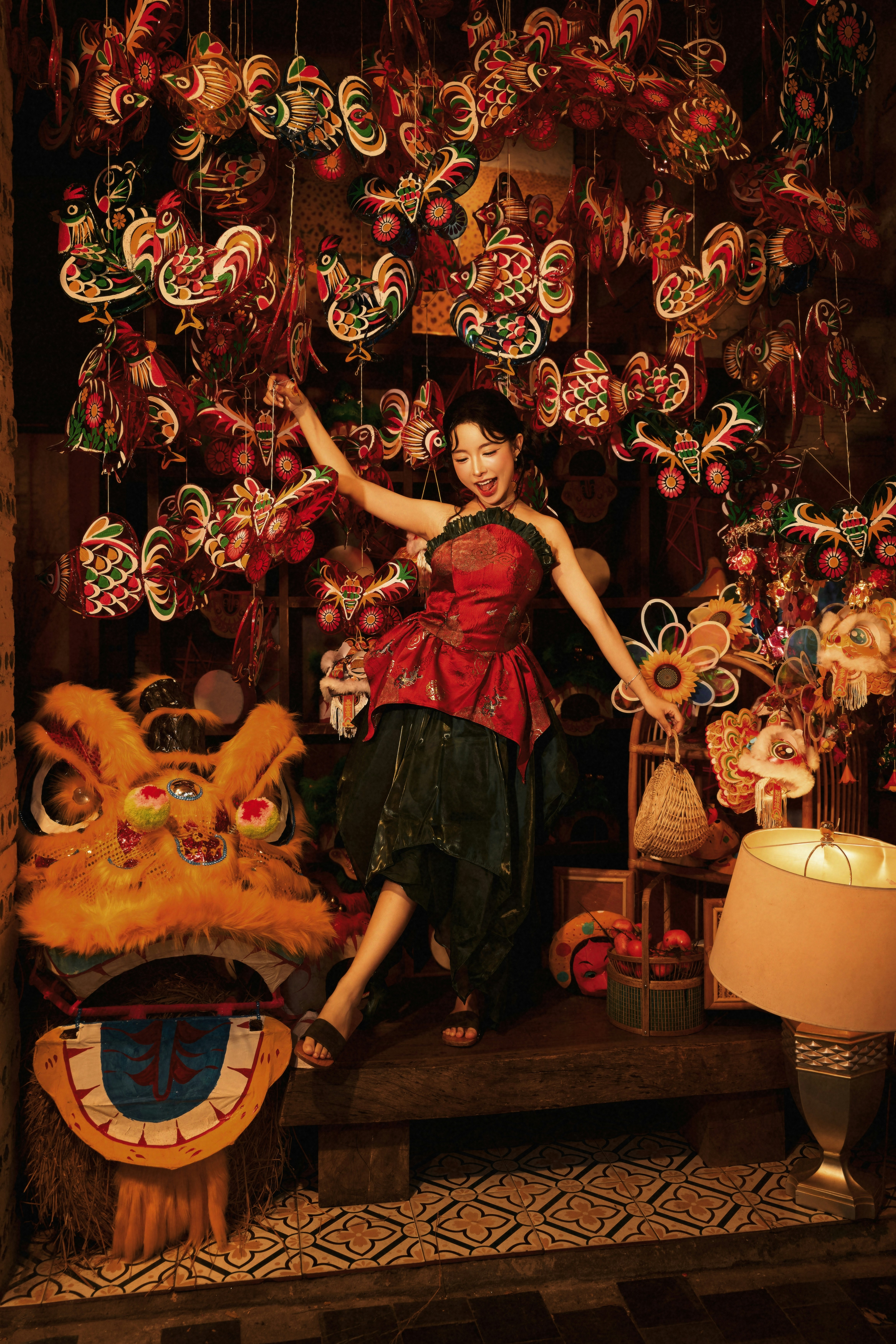 A woman in a red top posing among hanging colorful paper lanterns