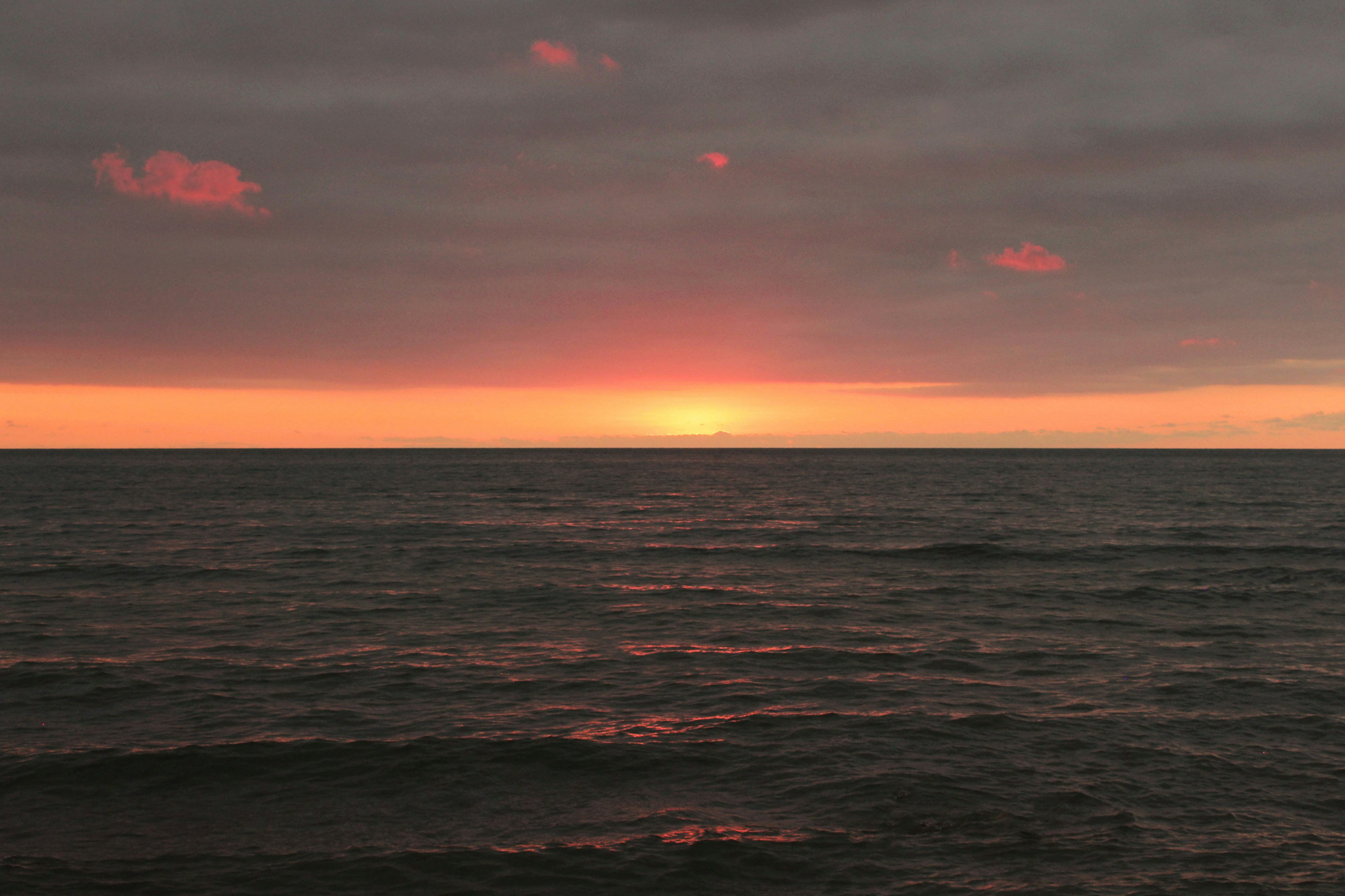Sol bajo brillando en el horizonte sobre el oscuro y ondulante agua del océano