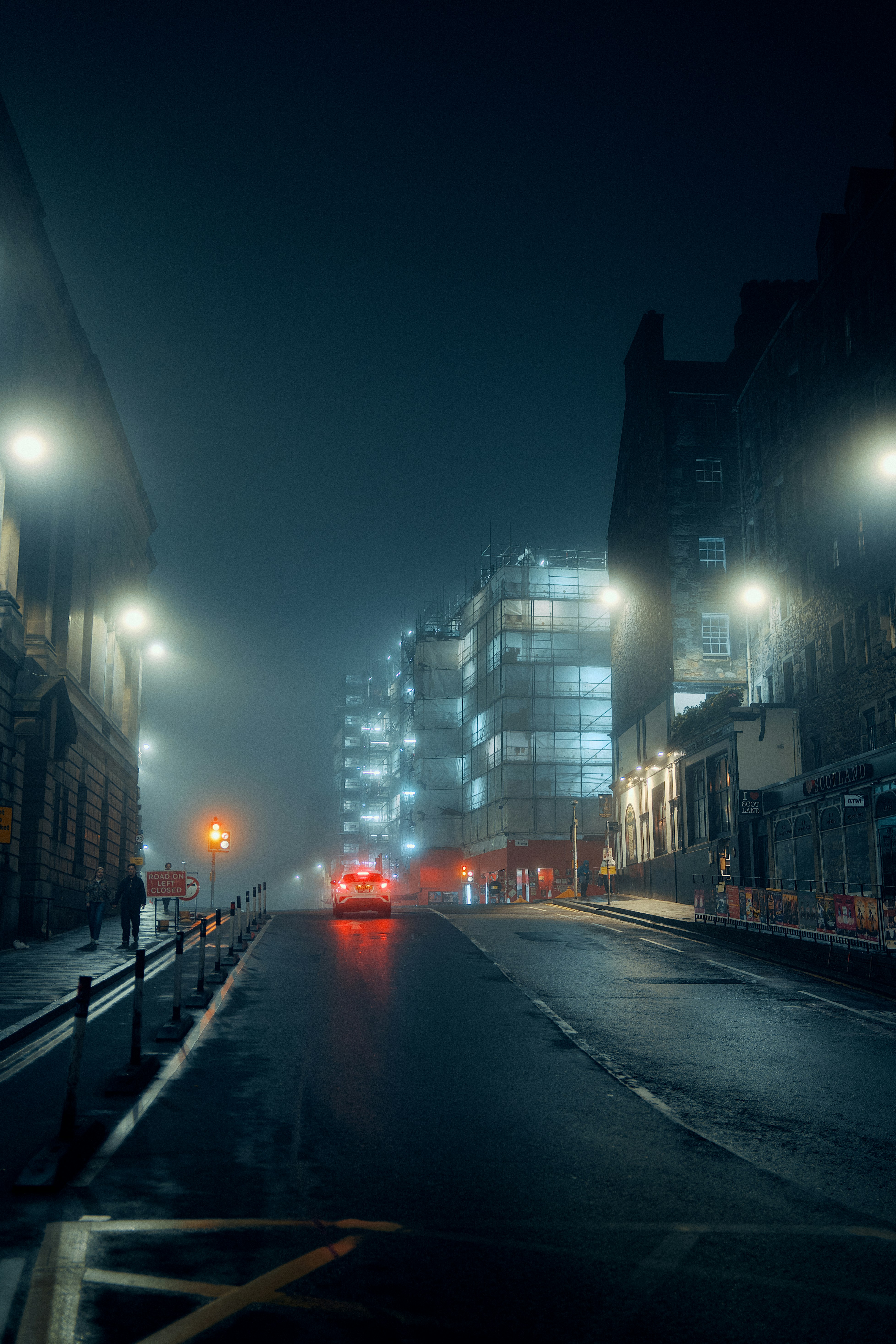 A car driving down a foggy city street at night with glowing streetlights - 相关推荐