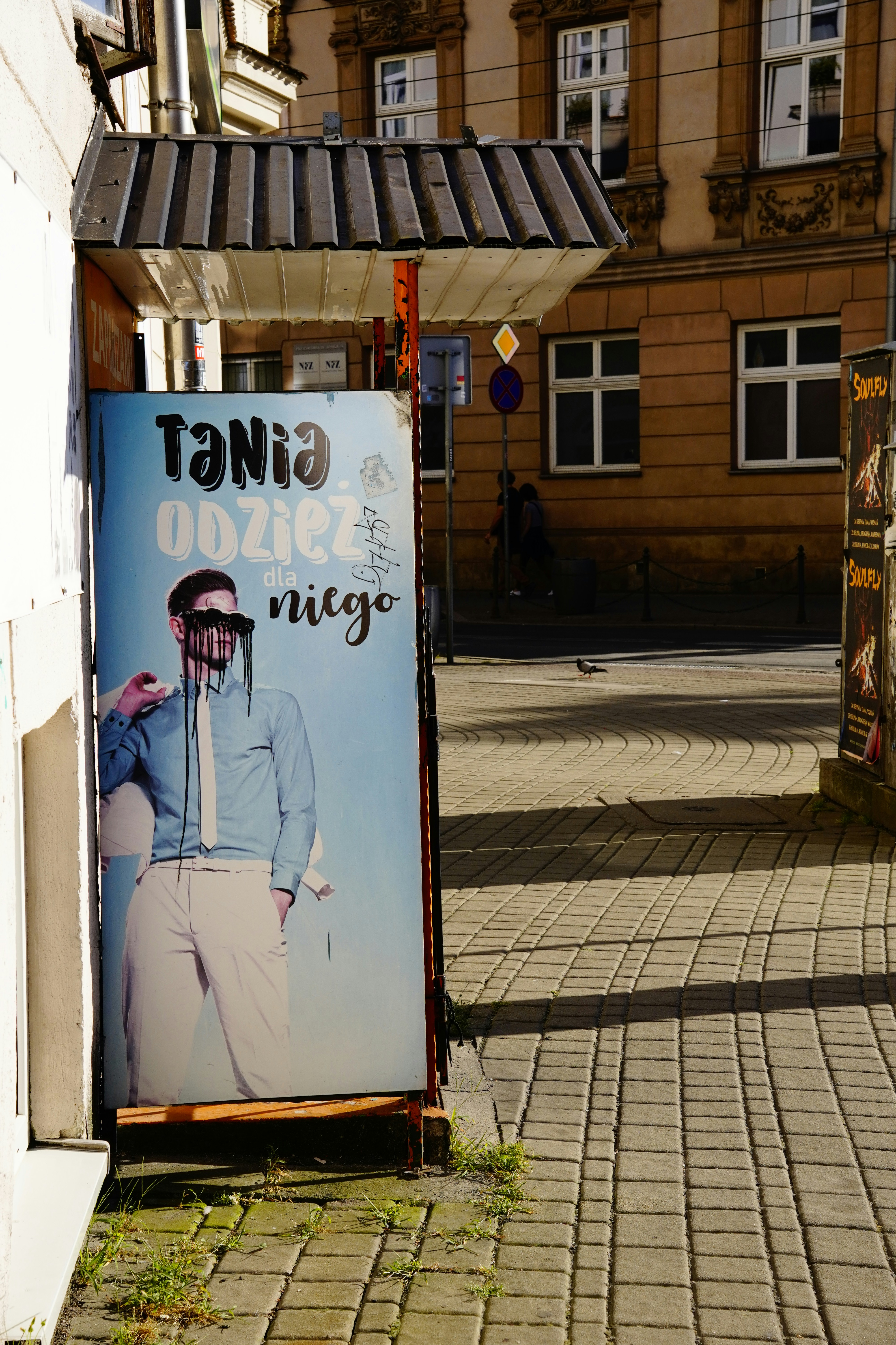 A street advertisement featuring a man in a blue shirt on a paved sidewalk