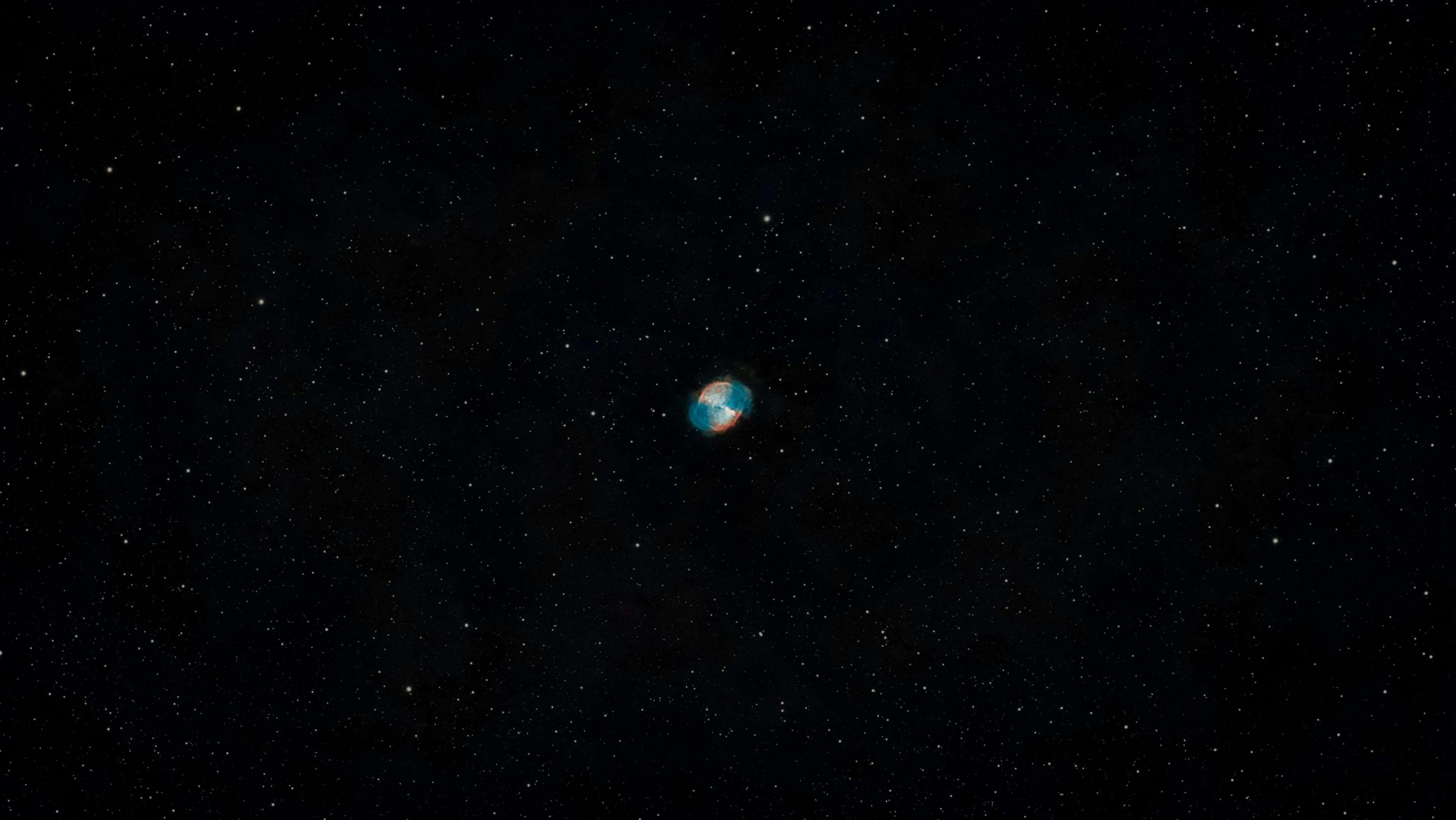 The Dumbbell Nebula glowing in blue and orange among scattered stars in space