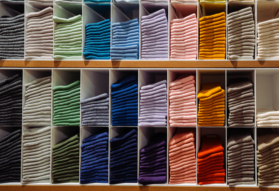 stacks of folded colourful socks sorted by colour on wooden shelves
