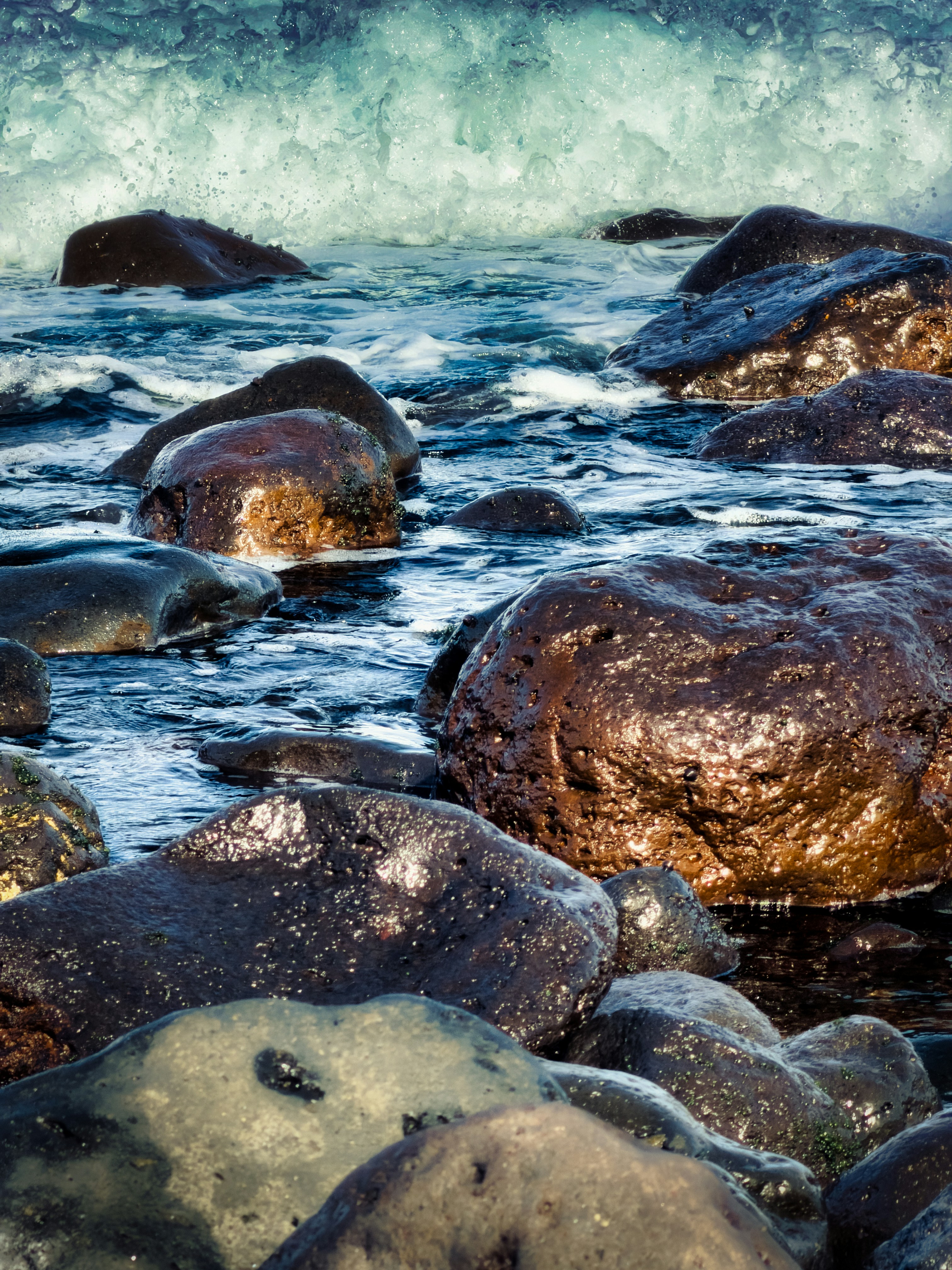 Ocean waves washing over dark wet rocks on a shoreline
