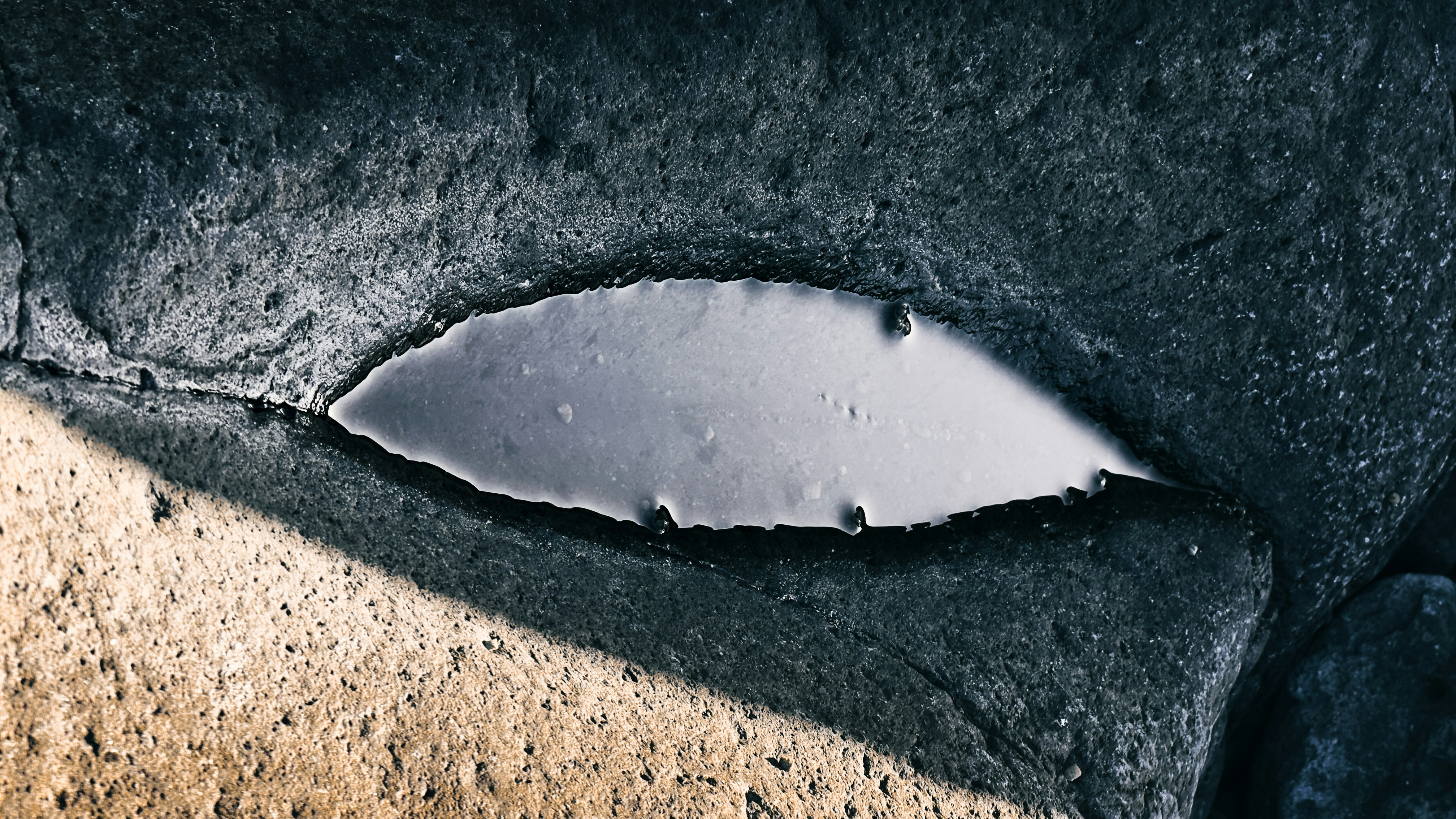 A small pool of water inside a dark rock crevice