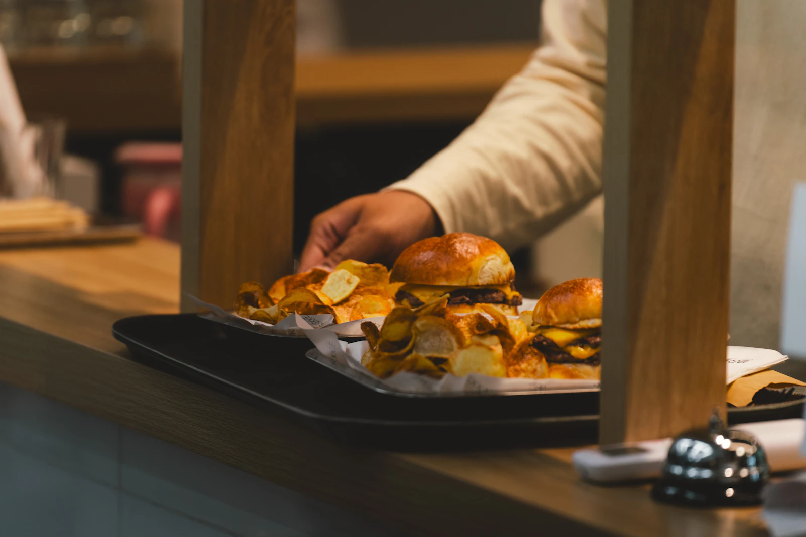 Plateau de burgers et de chips posé sur le comptoir d'un snack, près de la sonnette de service