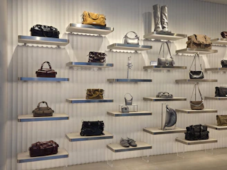 Handbags and shoes displayed on floating shelves against a white ribbed wall