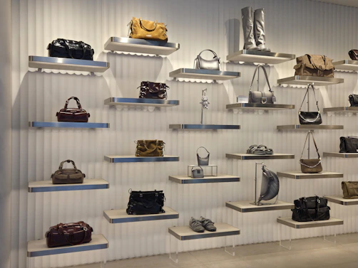 Handbags and shoes displayed on floating shelves against a white ribbed wall