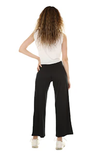 A woman with curly hair in a white top and black trousers