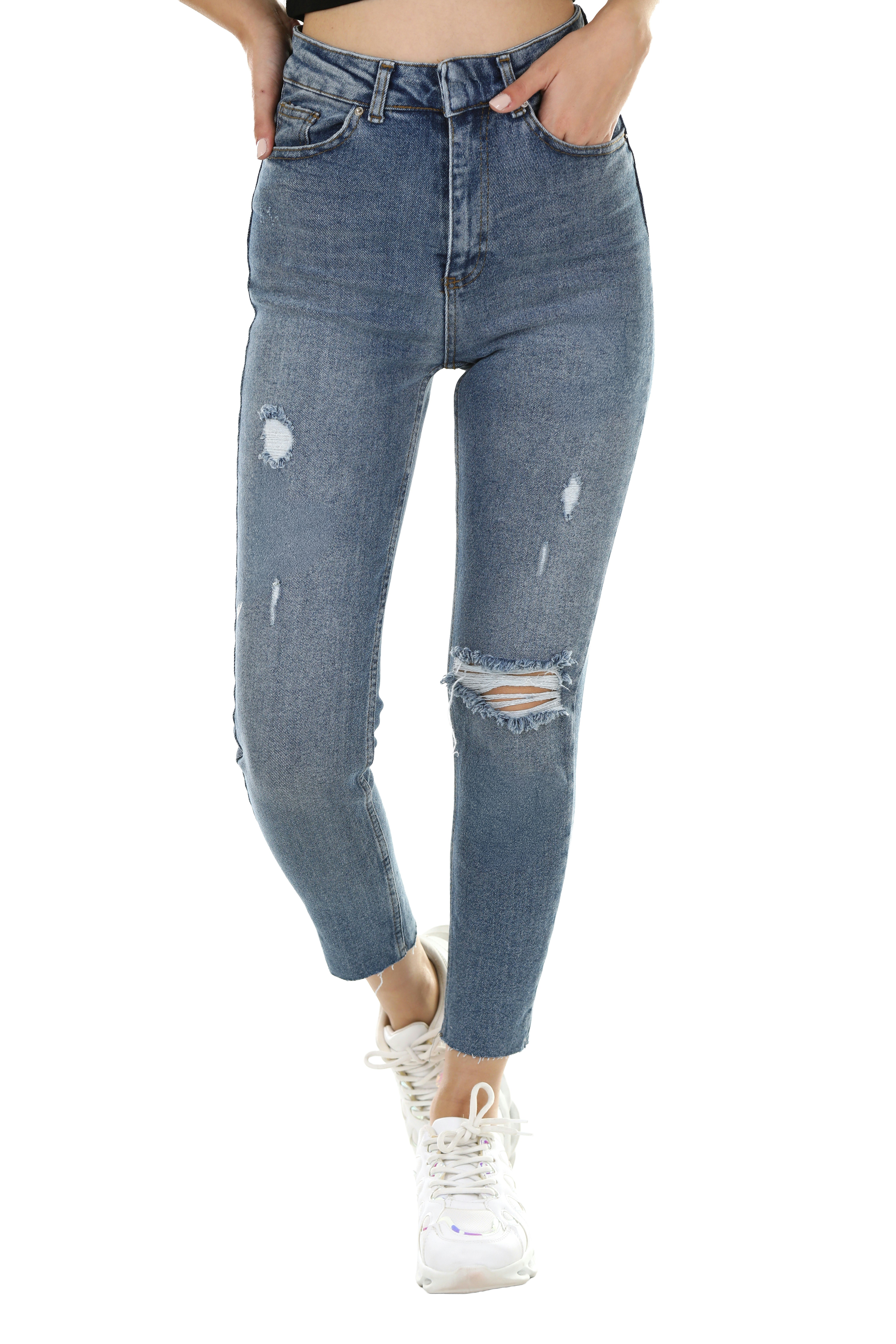 A person wearing distressed blue denim jeans and white sneakers against a white background